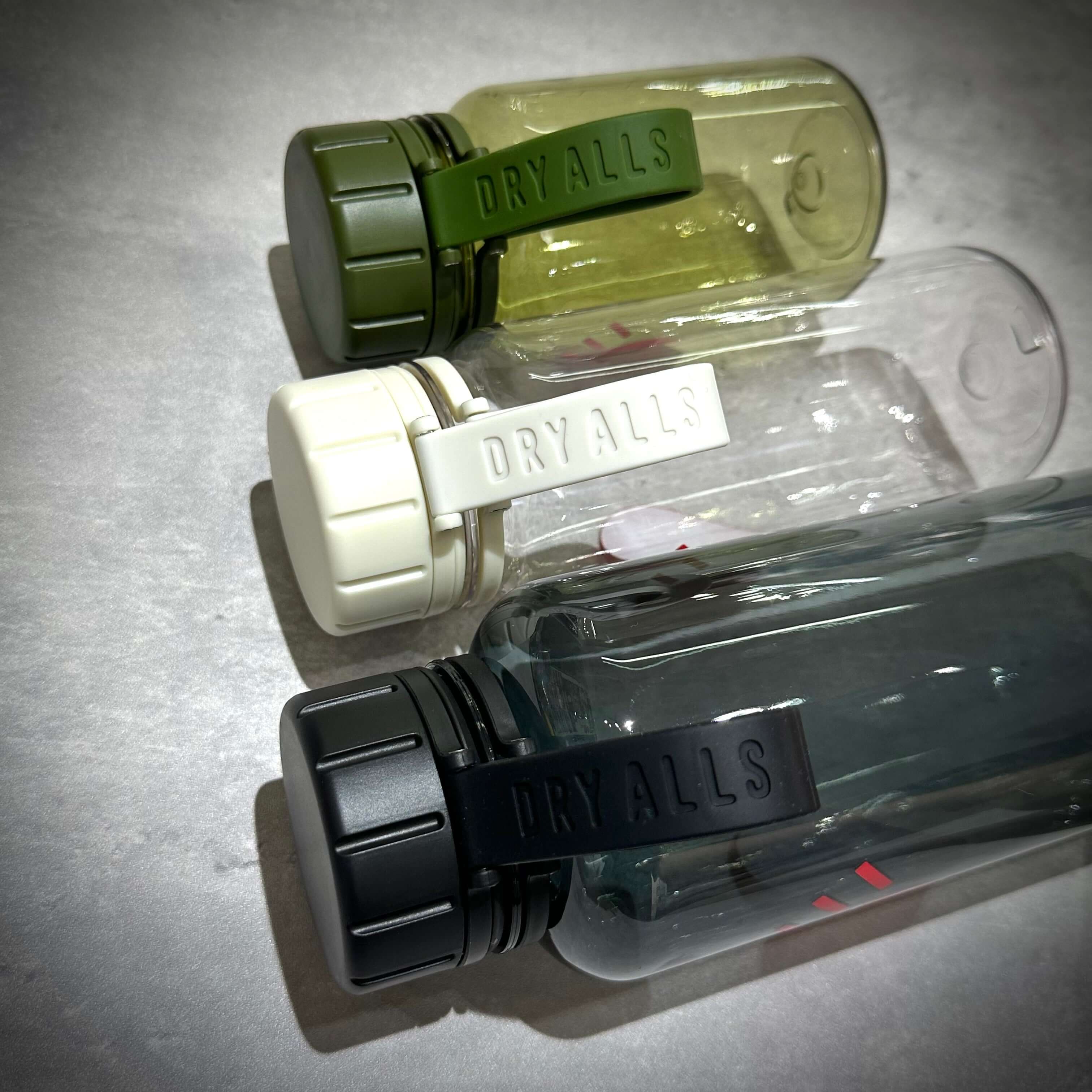 Human Made Water Bottle in three color variations: green, white, and black with dry all straps.