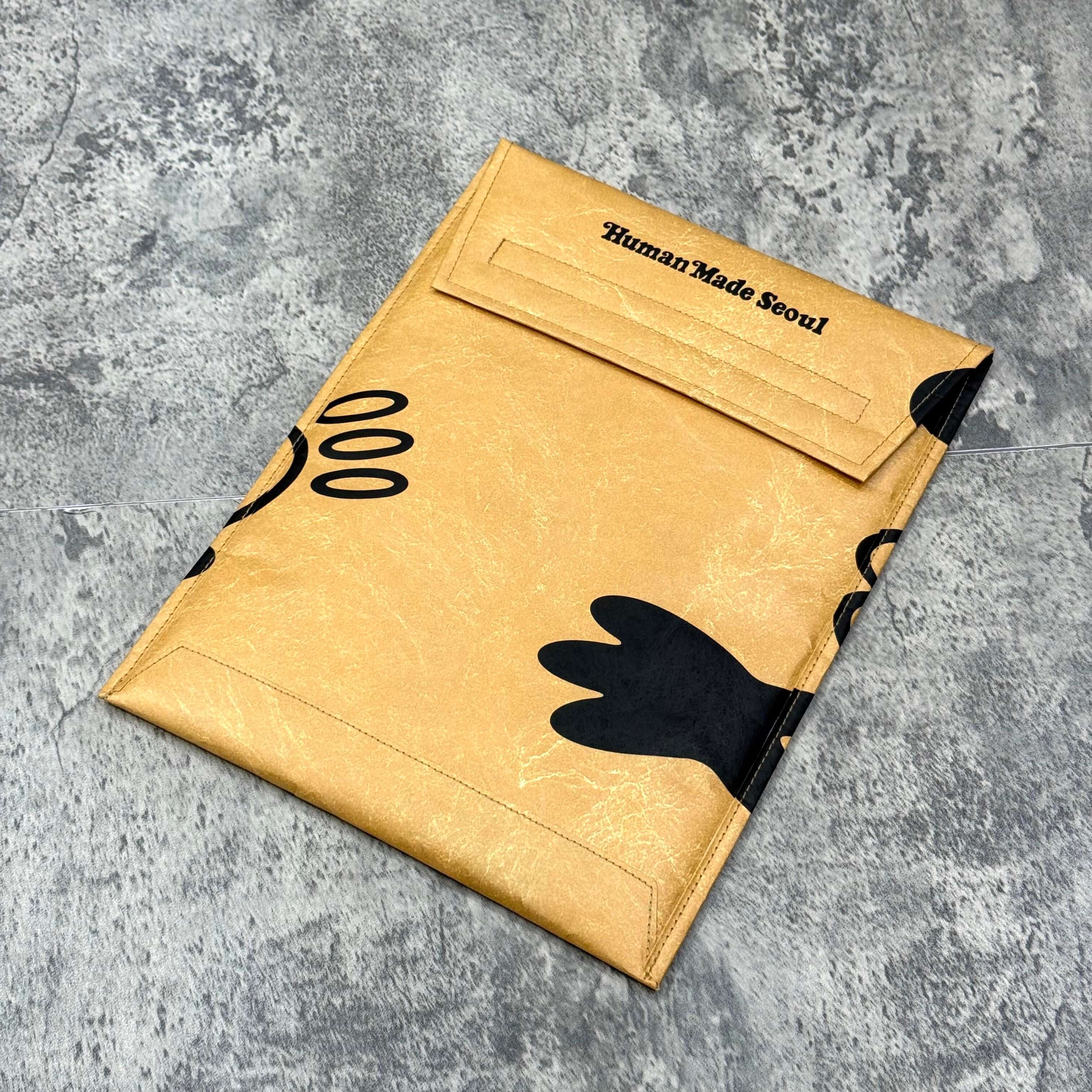 Human Made x VERDY Jamsil Exclusive Tablet Case in gold with black illustrations on a textured background.