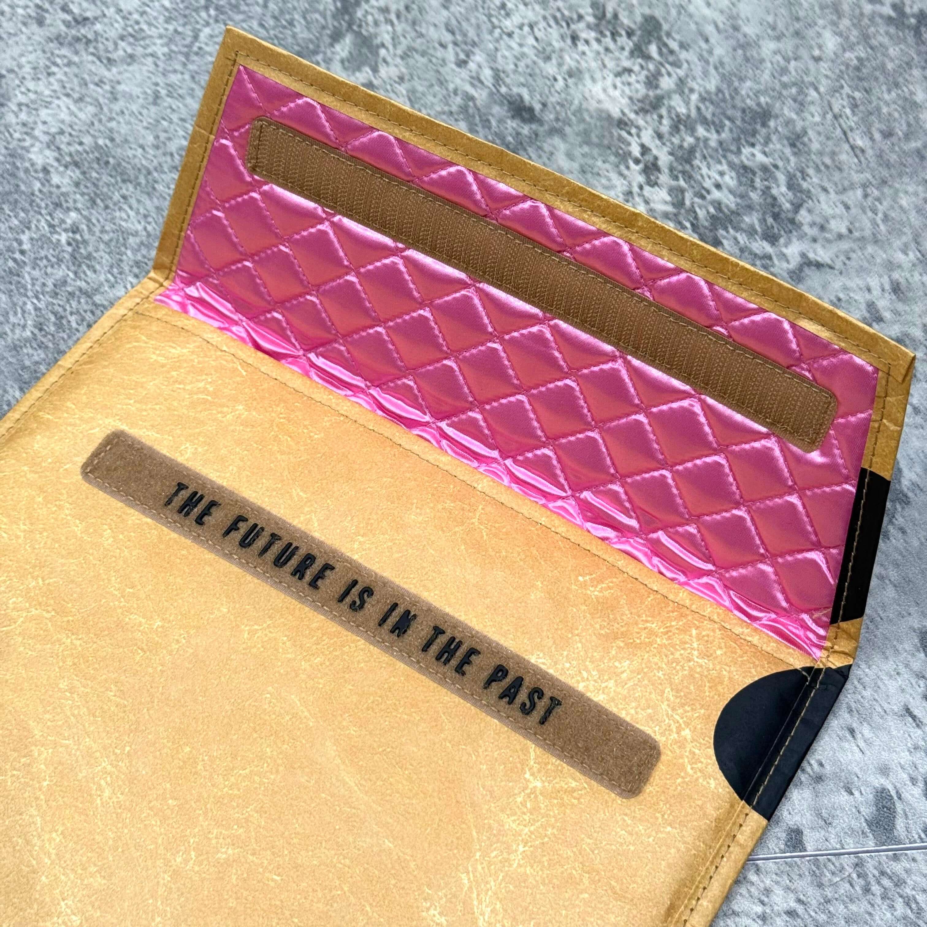 Interior view of Human Made x VERDY Jamsil Exclusive Tablet Case showcasing quilted pink lining and text 'The future is in the past'.