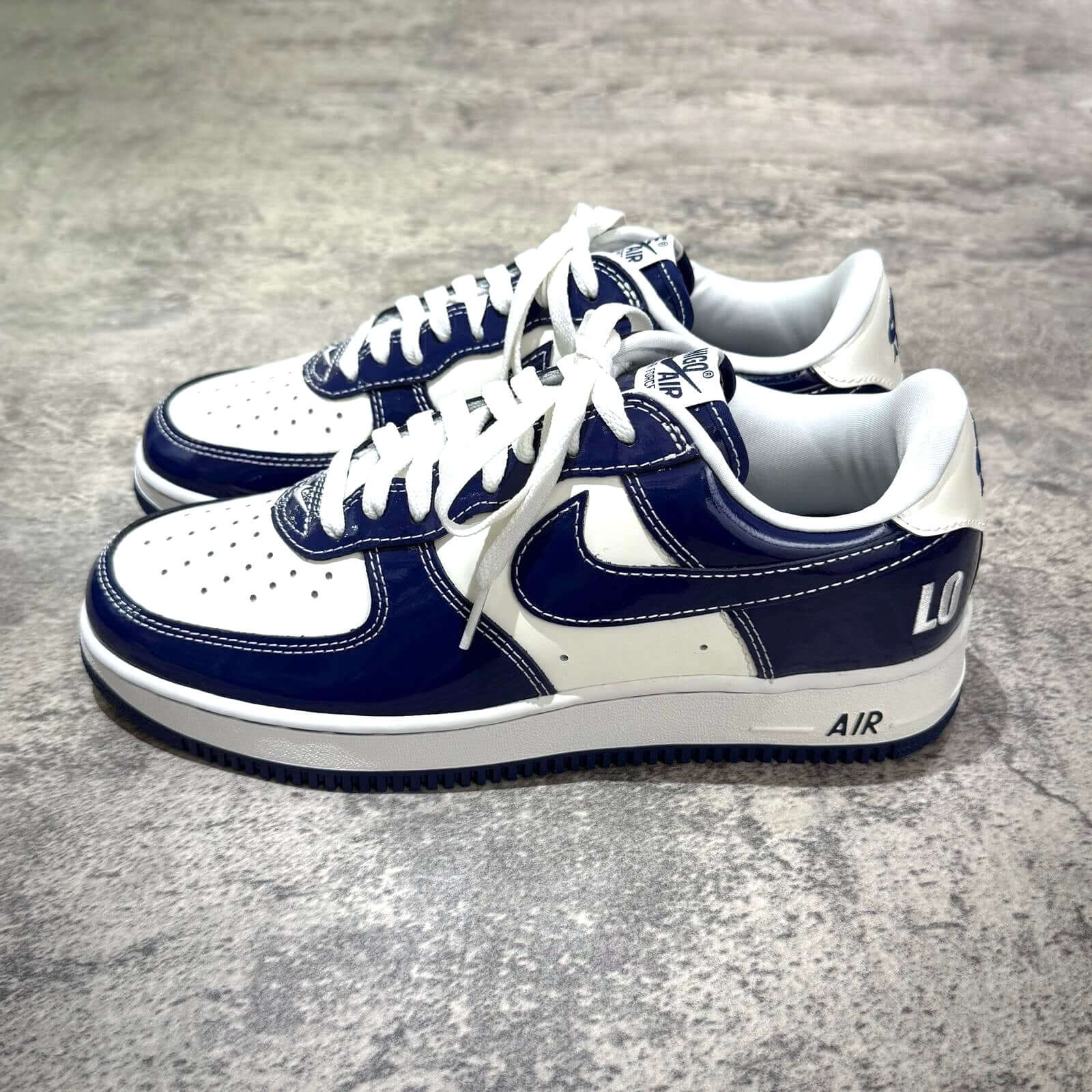 Nigo x Nike Air Force 1 LAST ORGY 2 sneaker featuring navy and white color scheme, side view on a textured surface.