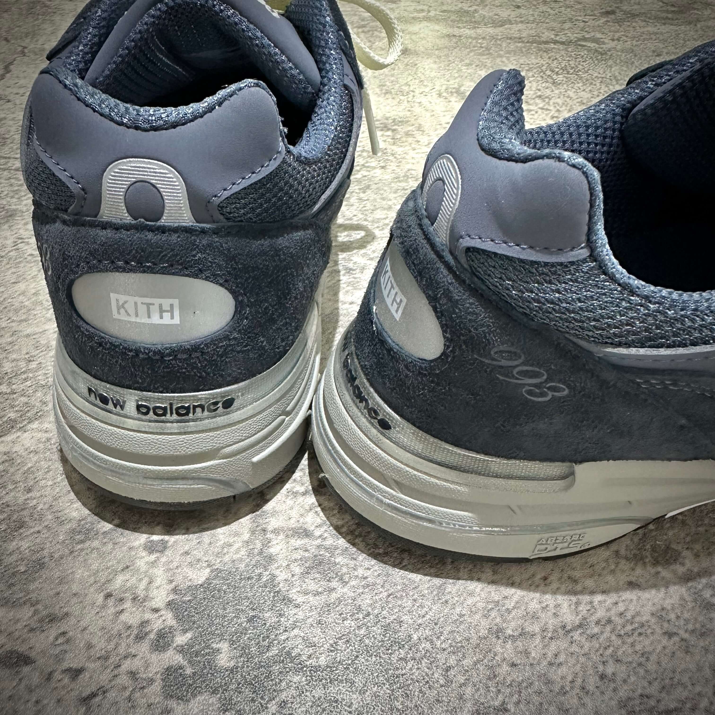 MiUSA Kith x New Balance 993 Asteroid close-up showing KITH branding and shoe details on grey sneakers.
