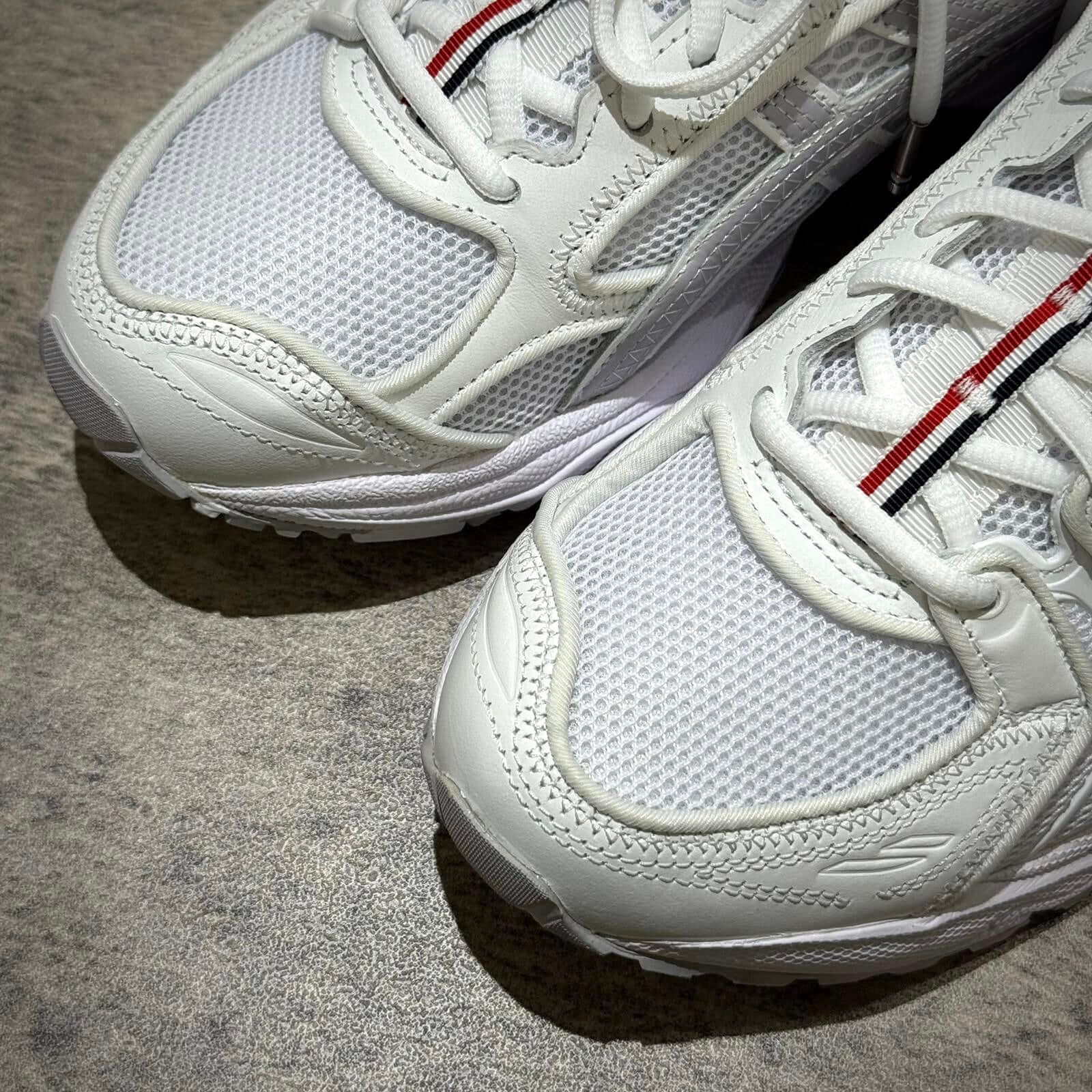 Thom Browne x Asics Gel-Kayano 14 - White sneakers close-up showing mesh and leather details.