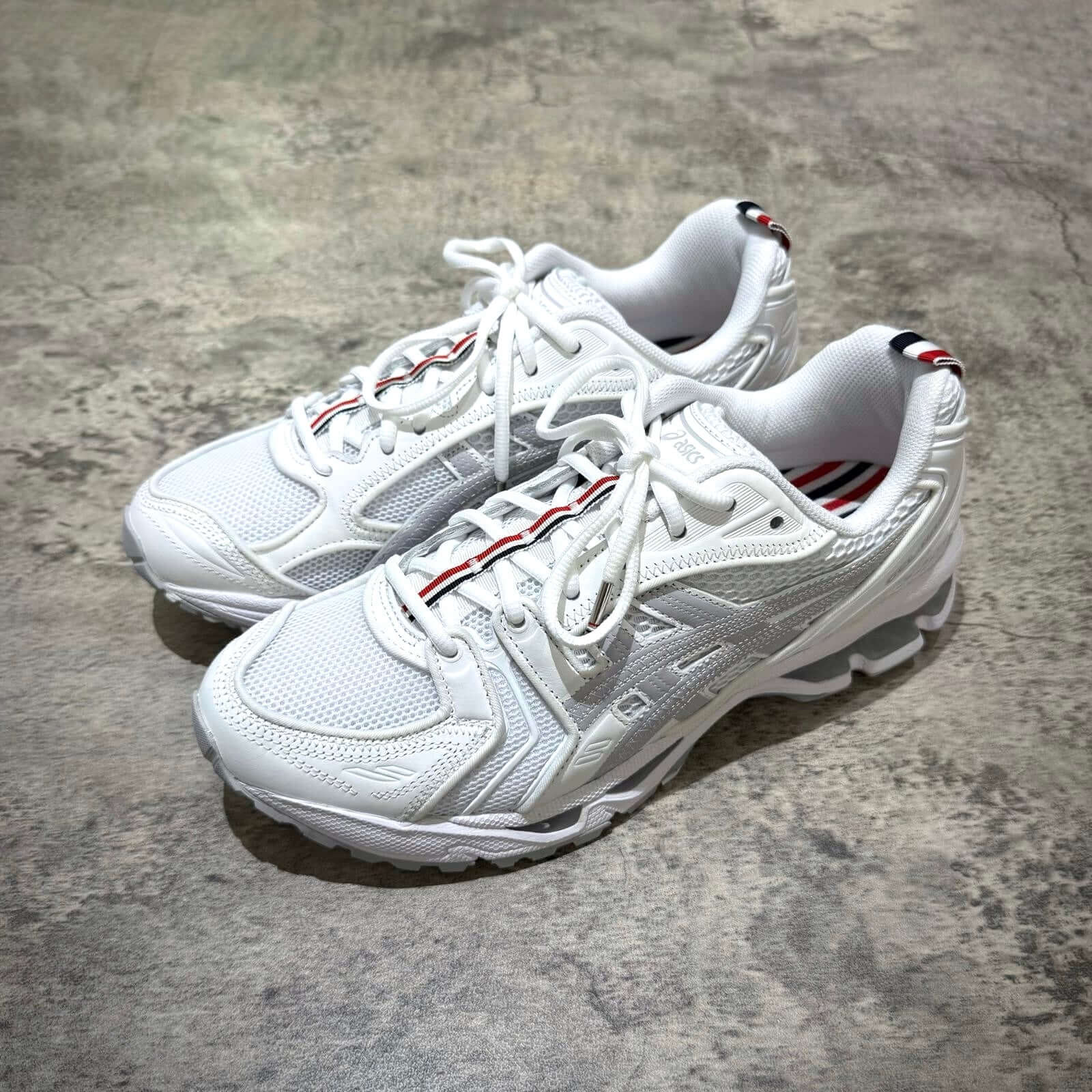 Thom Browne x Asics Gel-Kayano 14 sneakers in white showcasing a sporty design with stylish details.
