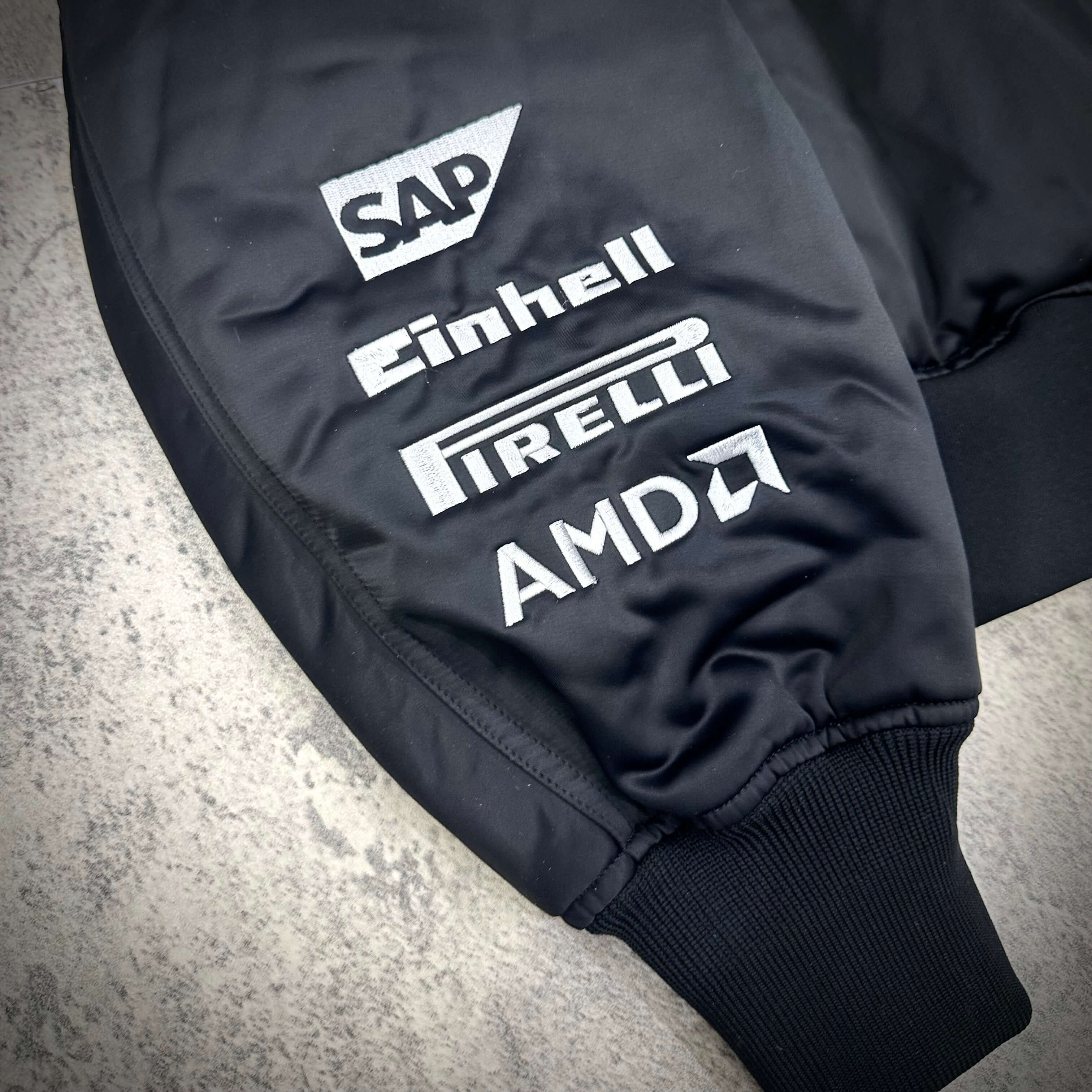Close-up of the sleeve featuring sponsor logos on the Y-3 x Mercedes AMG Petronas F1 Team Jacket.