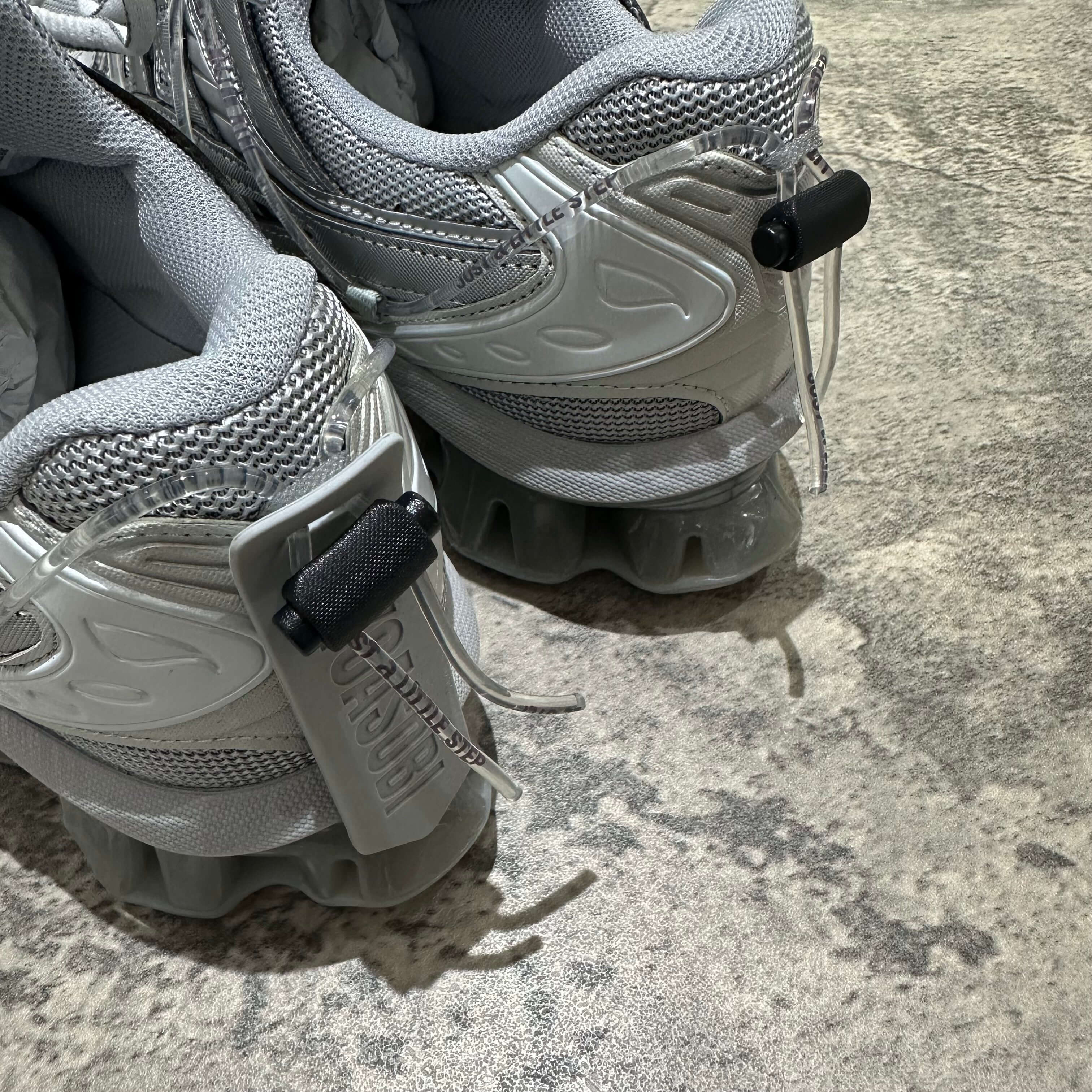 Close-up of Yoasobi x Asics Gel Kinetic Fluent Y shoes in Piedmont Grey and Pure Silver, showcasing rear design details.