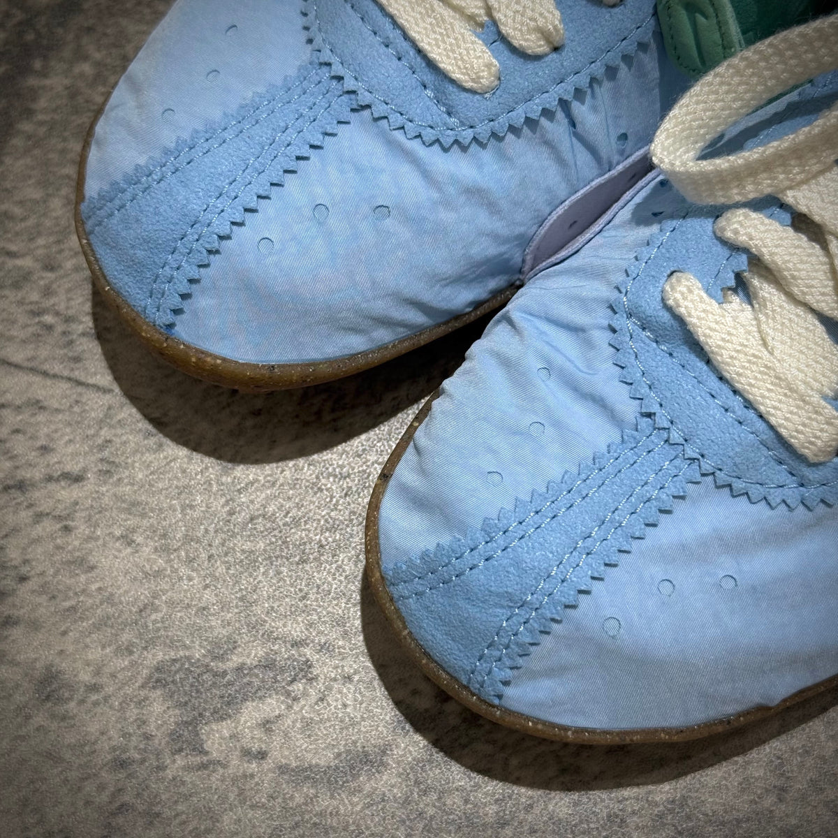 Jacquemus x Nike Moon Shoe SP - Emerald Rise HV8547-300 close-up of blue upper and laces on a textured surface.