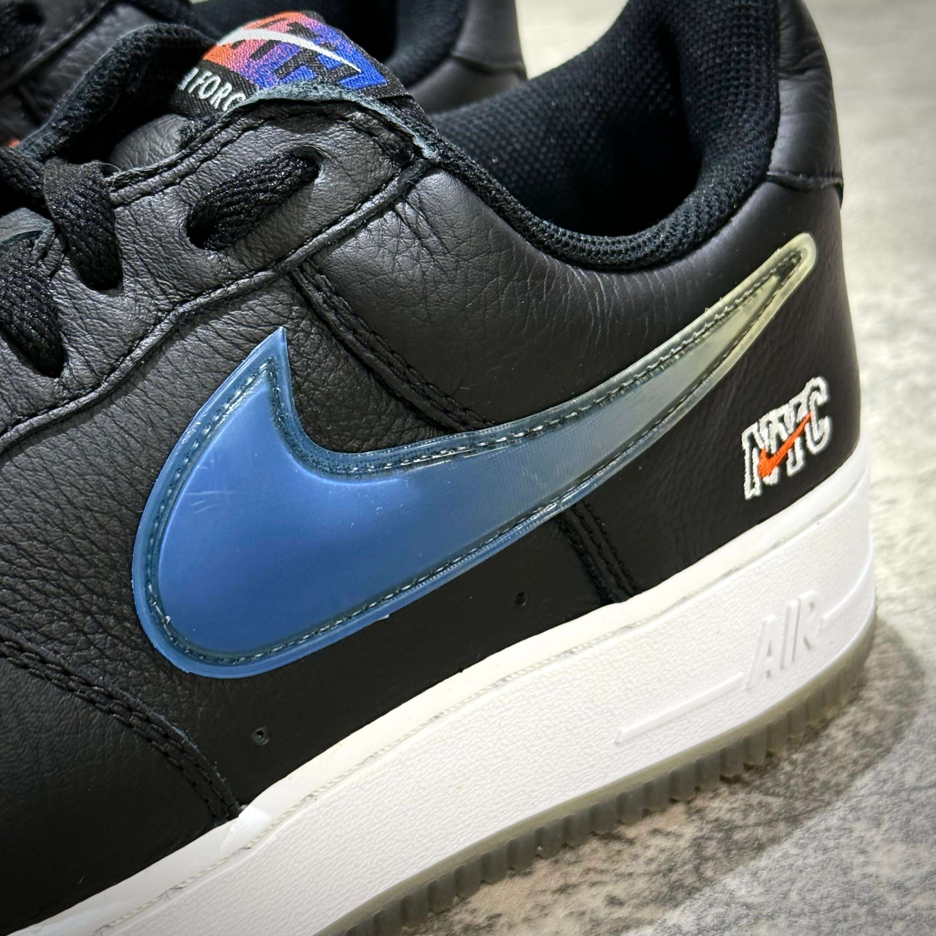 Close-up of KITH x Nike Air Force 1 Low Knicks featuring blue Swoosh and NYC logo on black leather.