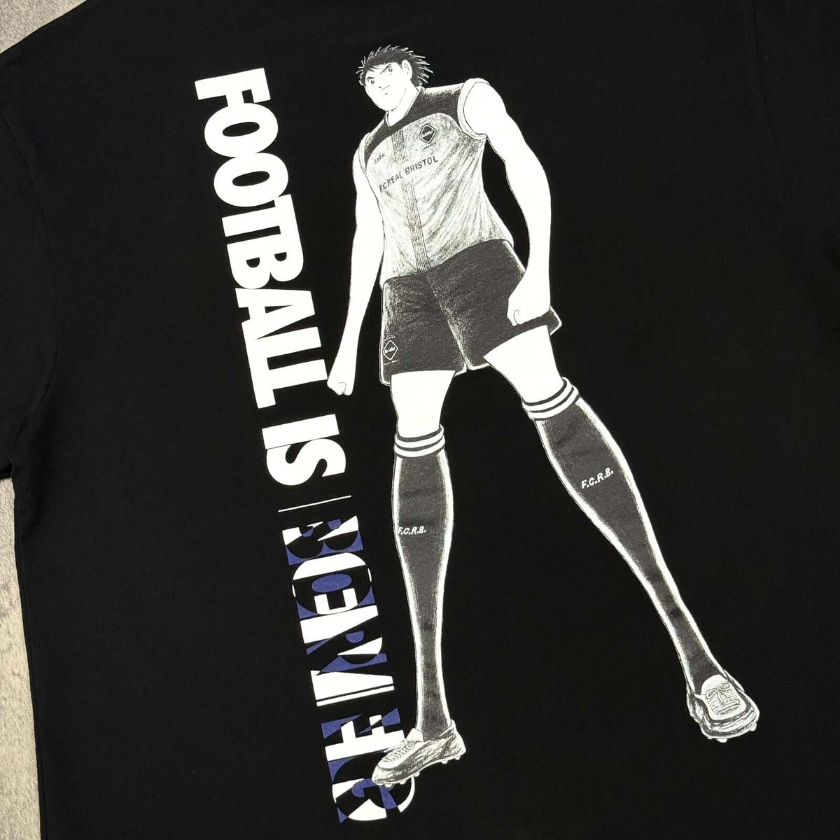 Kojiro Hyuga x F.C.Real Bristol On The Back Tee featuring anime-style print with 'Football is Forever' slogan.