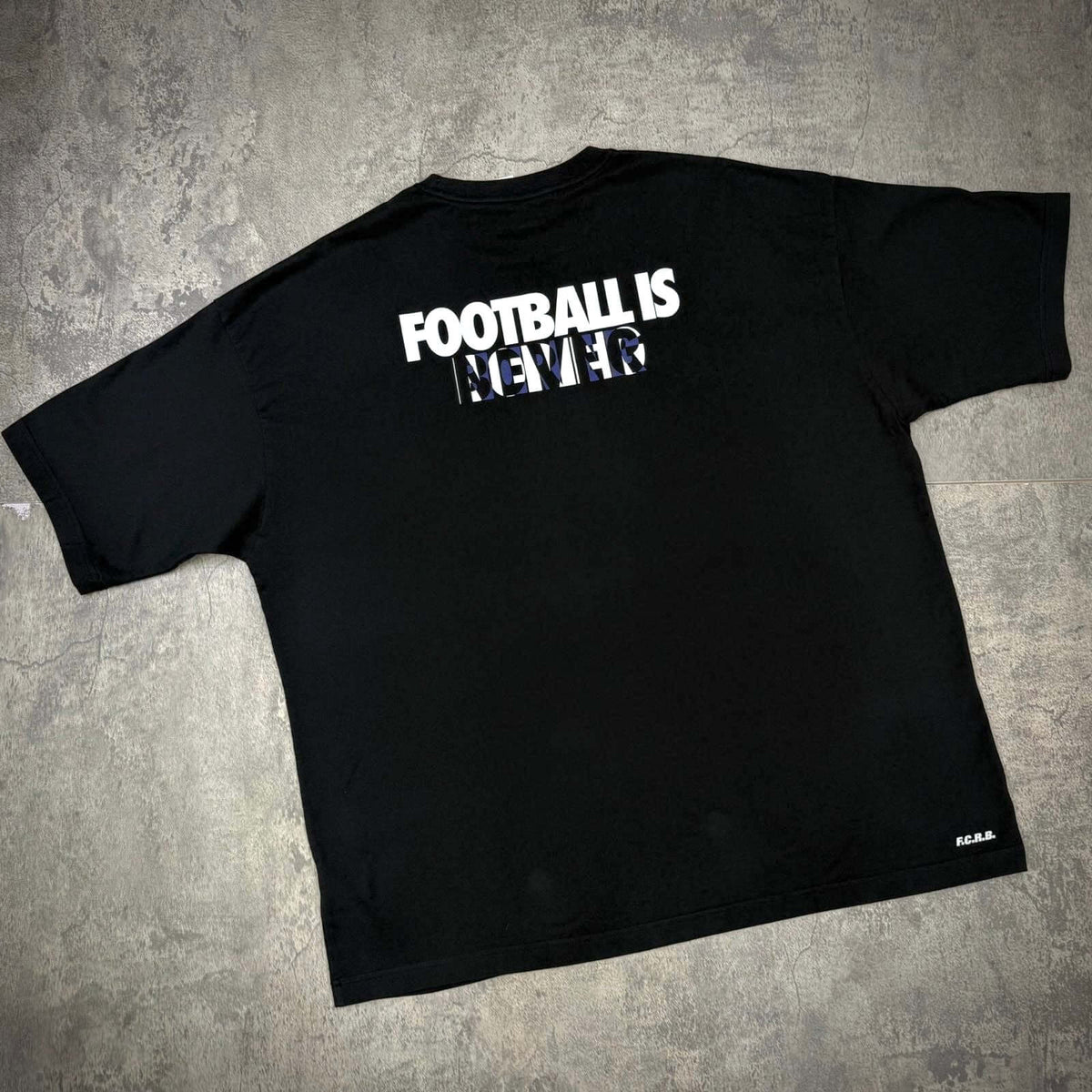 Kojiro Hyuga x F.C.Real Bristol On The Front Baggy Tee featuring the text 'FOOTBALL IS NEVER' on the back.