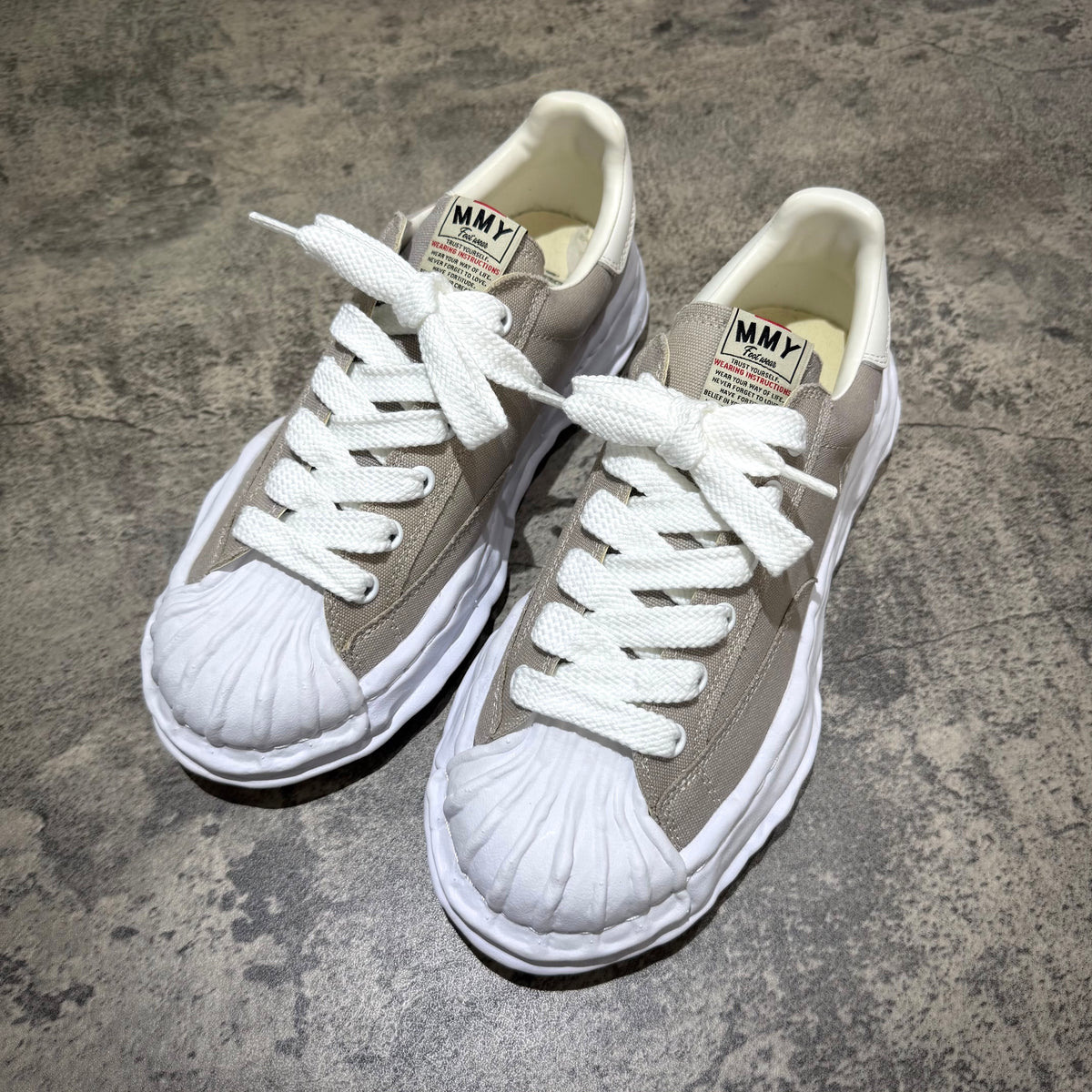 MMY BLAKEY OG Canvas in Gray with white laces and rubber toe cap on a textured surface.