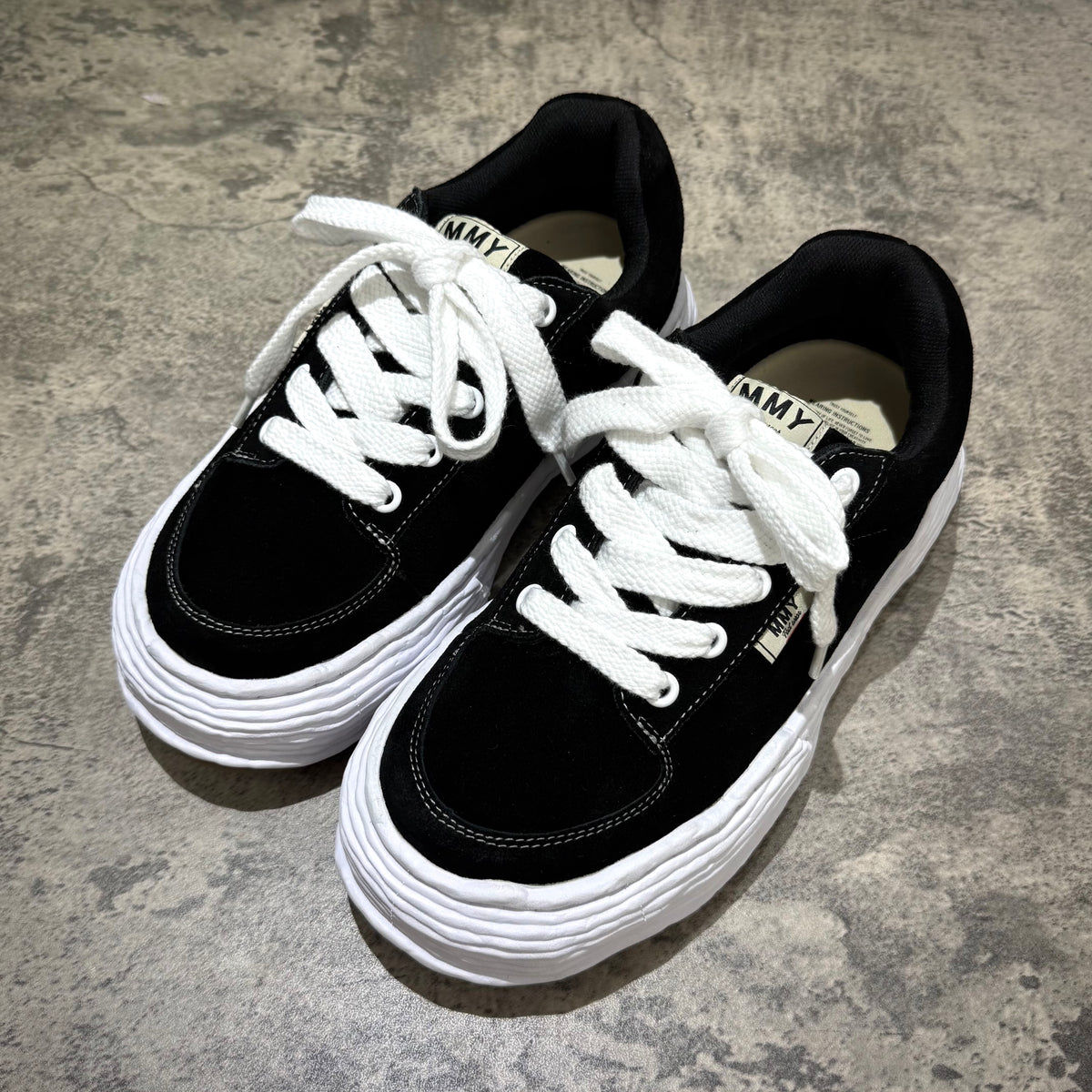 MMY Oliver Suede Low - Black stylish sneakers with white laces on a textured surface.