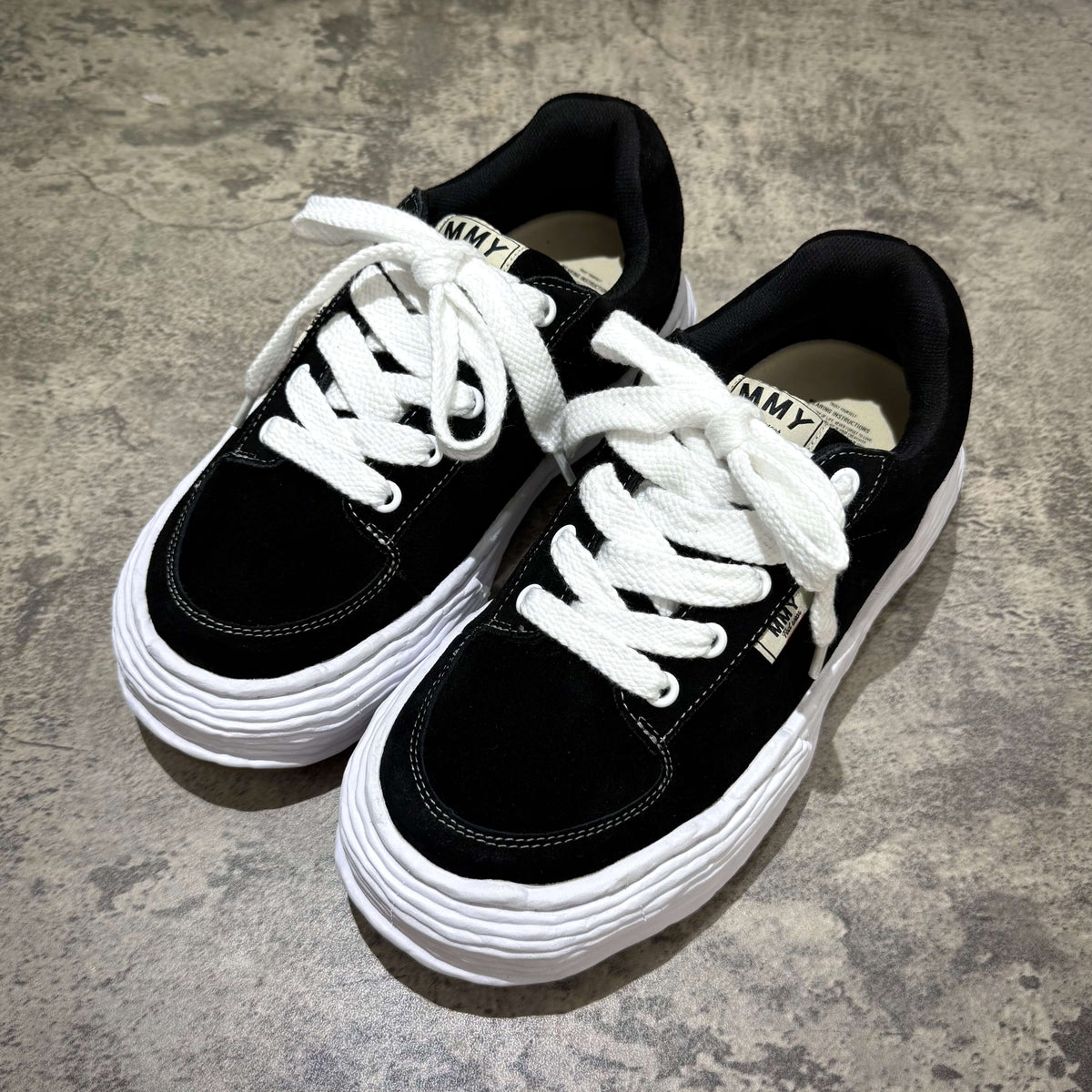 MMY Oliver Suede Low - Black stylish sneakers with white laces on a textured surface.