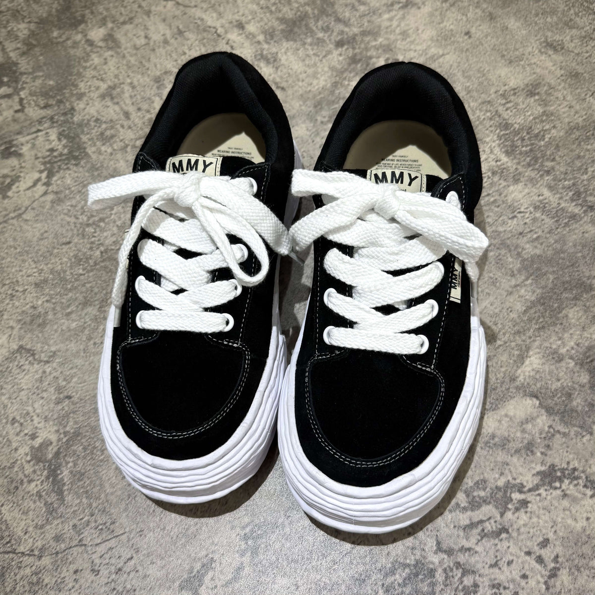 MMY Oliver Suede Low - Black sneakers with white laces and textured sole on a grey background.