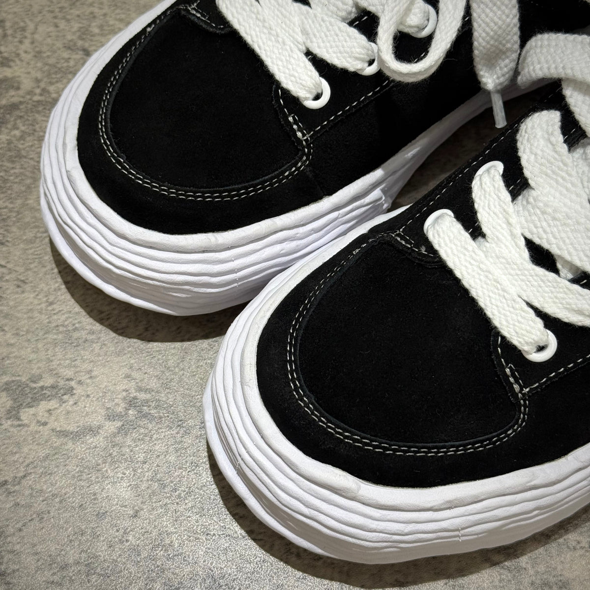 MMY Oliver Suede Low - Black close-up view showcasing black suede upper and white laces.