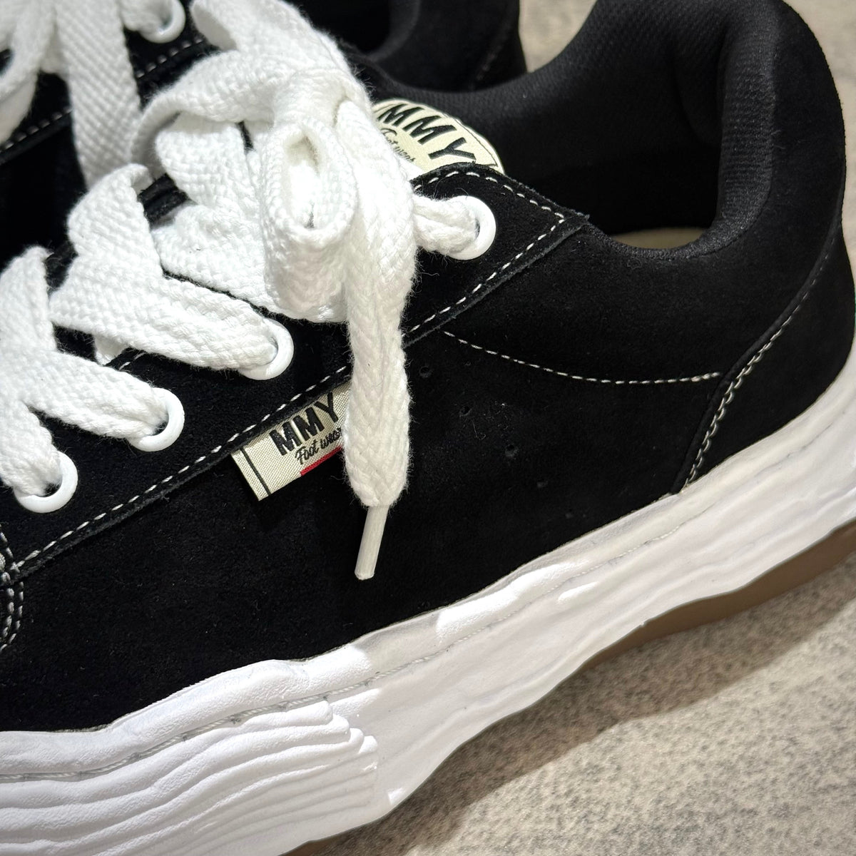 MMY Oliver Suede Low - Black sneaker with white laces and rubber outsole, showing quality suede material and logo.