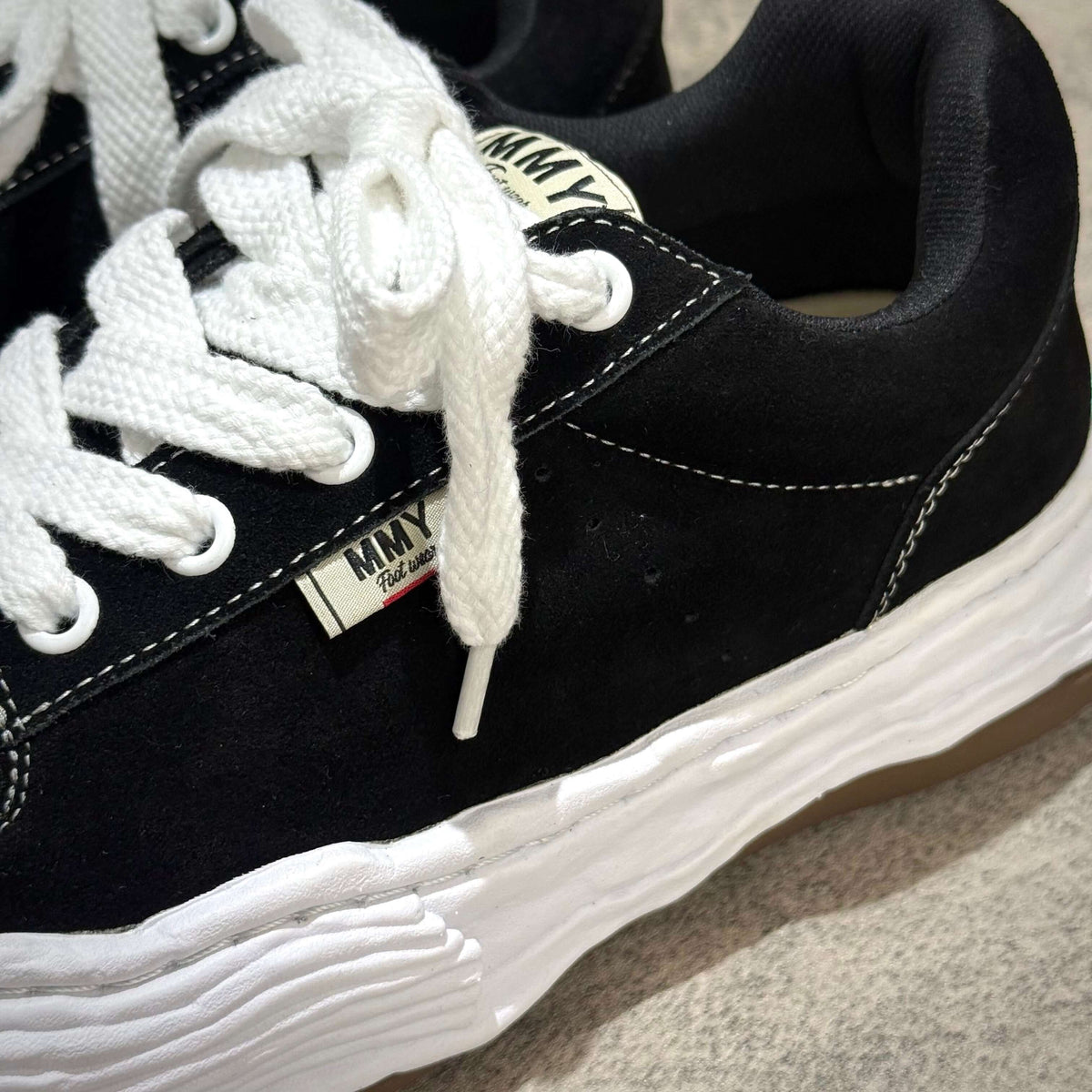 MMY Oliver Suede Low - Black sneaker with white laces and rubber outsole, showing quality suede material and logo.