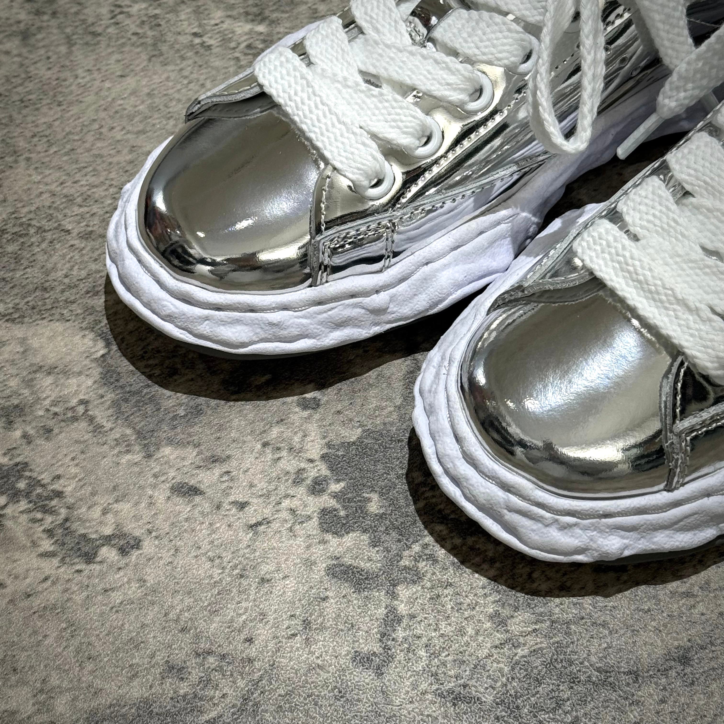 MMY CHARLES OG Sole Leather - Silver sneaker close-up showing shiny silver exterior and white laces.
