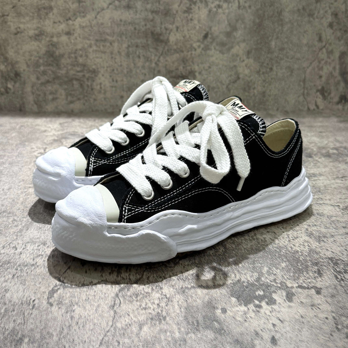 MMY HANK OG Canvas - Black sneakers with white laces and rubber soles on a textured background.