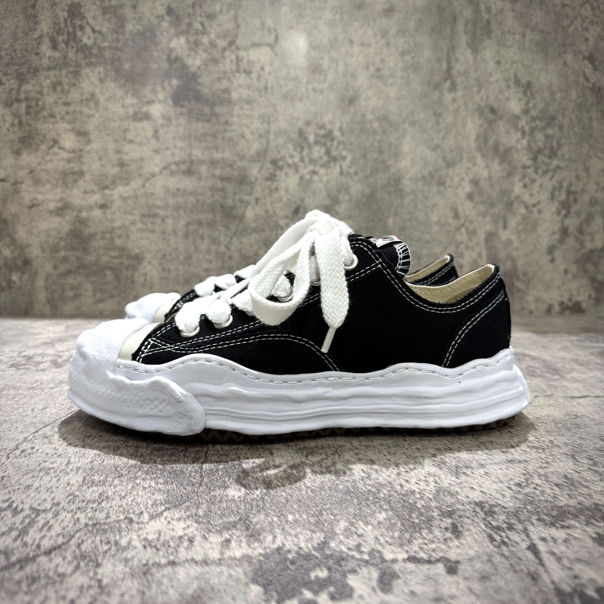 MMY HANK OG Canvas - Black side view with white laces and sole on a textured surface.