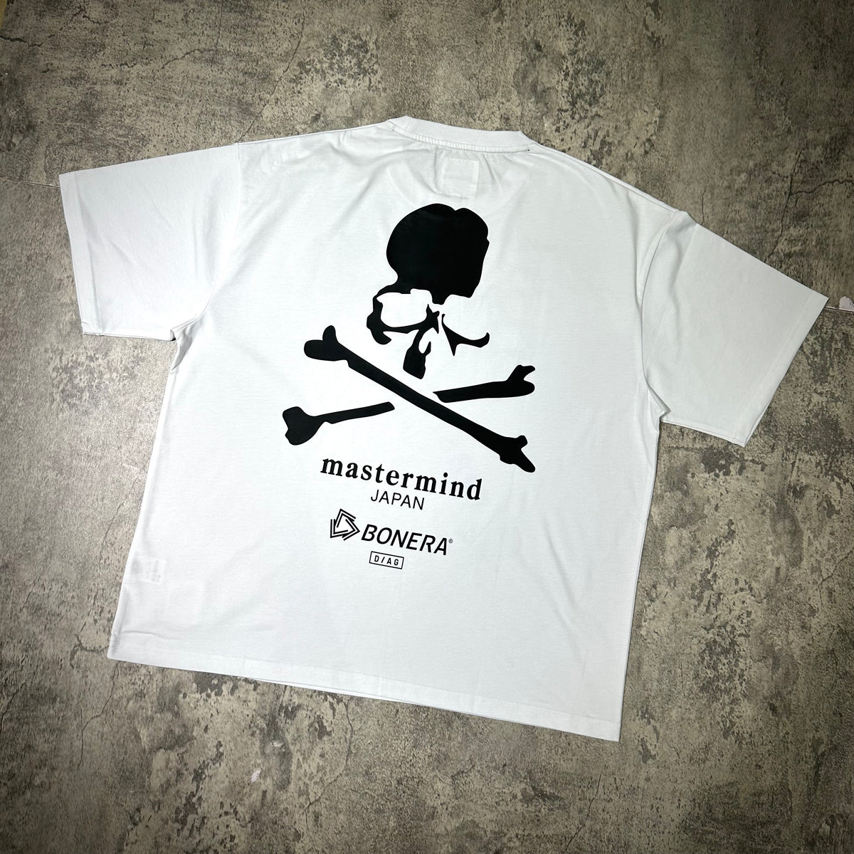 Back view of the Mastermind Japan x Bonera Tee featuring a skull and crossbones design on white fabric.