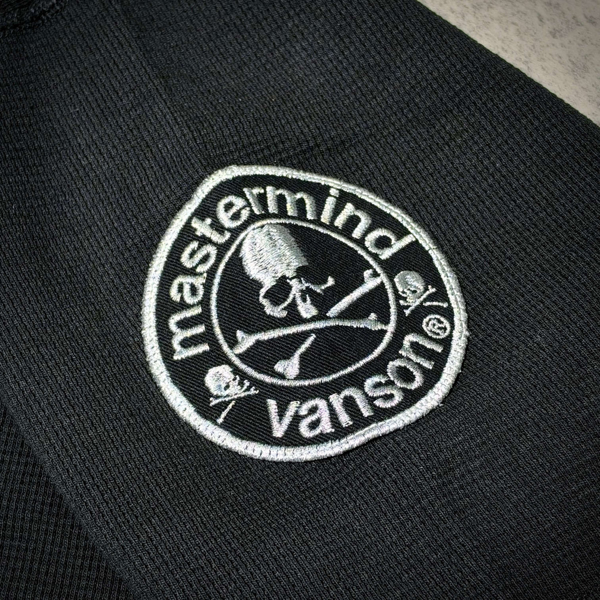 Close-up of the Mastermind World x Vanson logo patch featuring skull design on a black tee.