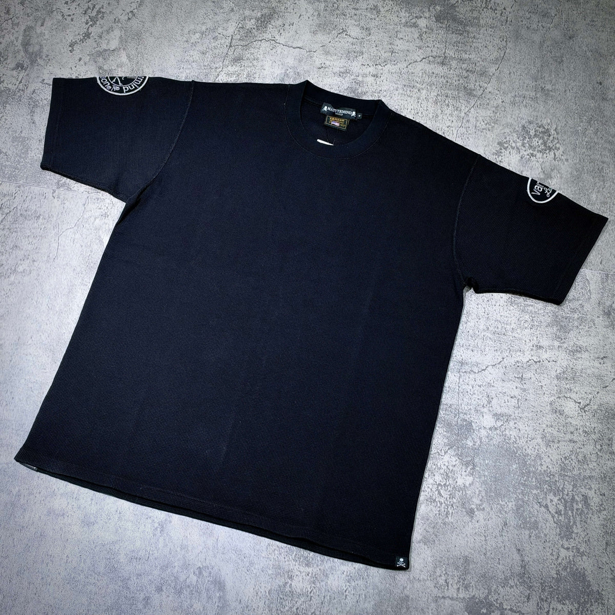 Mastermind World x Vanson Regular Fit Tee displayed on a flat surface, showcasing its black color and unique design.