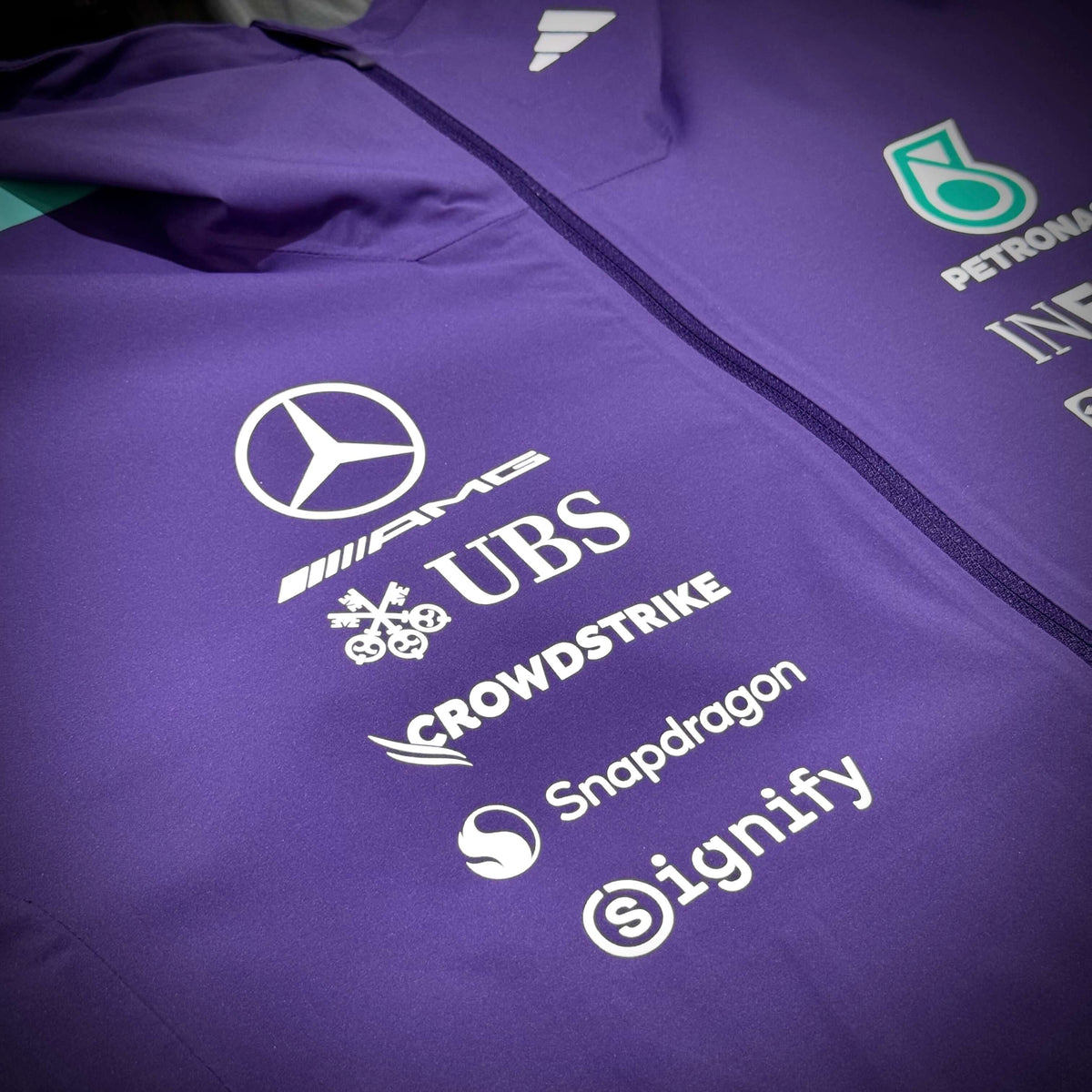 Mercedes-AMG Petronas Formula 1 Team Vanda Bloom Rain Jacket logo and sponsor details on a purple background.