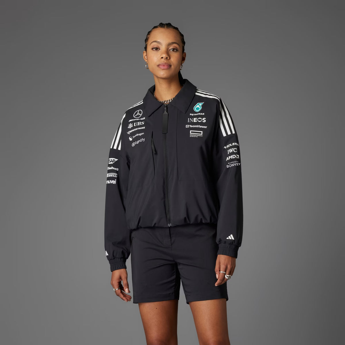 Adidas x Mercedes AMG Petronas 2025 F1 Team Jacket JX0751 worn by a woman against a gray background.
