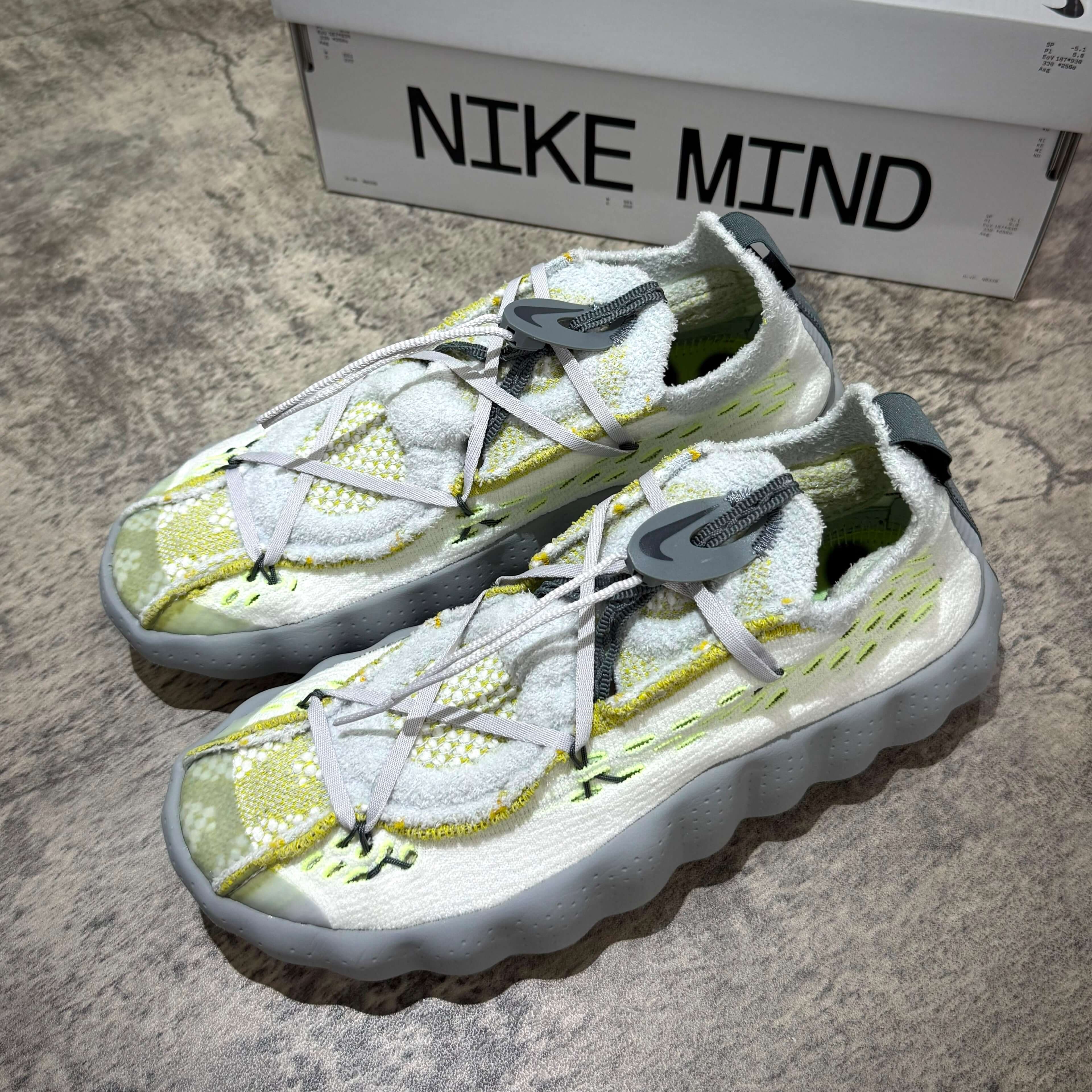 Nike Mind 002 Flyknit - Wolf Grey shoes with a vibrant yellow and white design, showcasing the unique Flyknit texture.