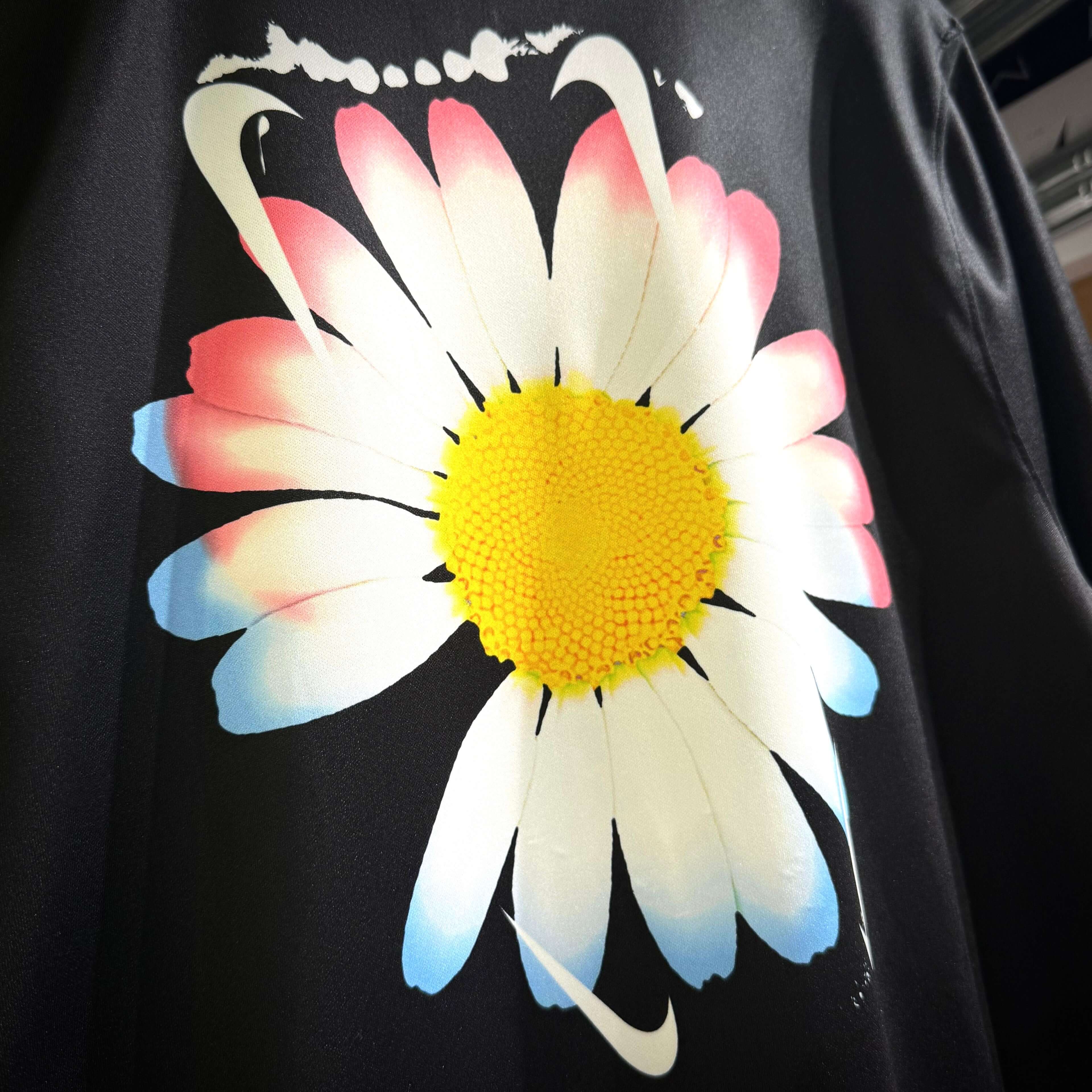 Nike flower graphic design featuring a daisy with vibrant colors on black background.