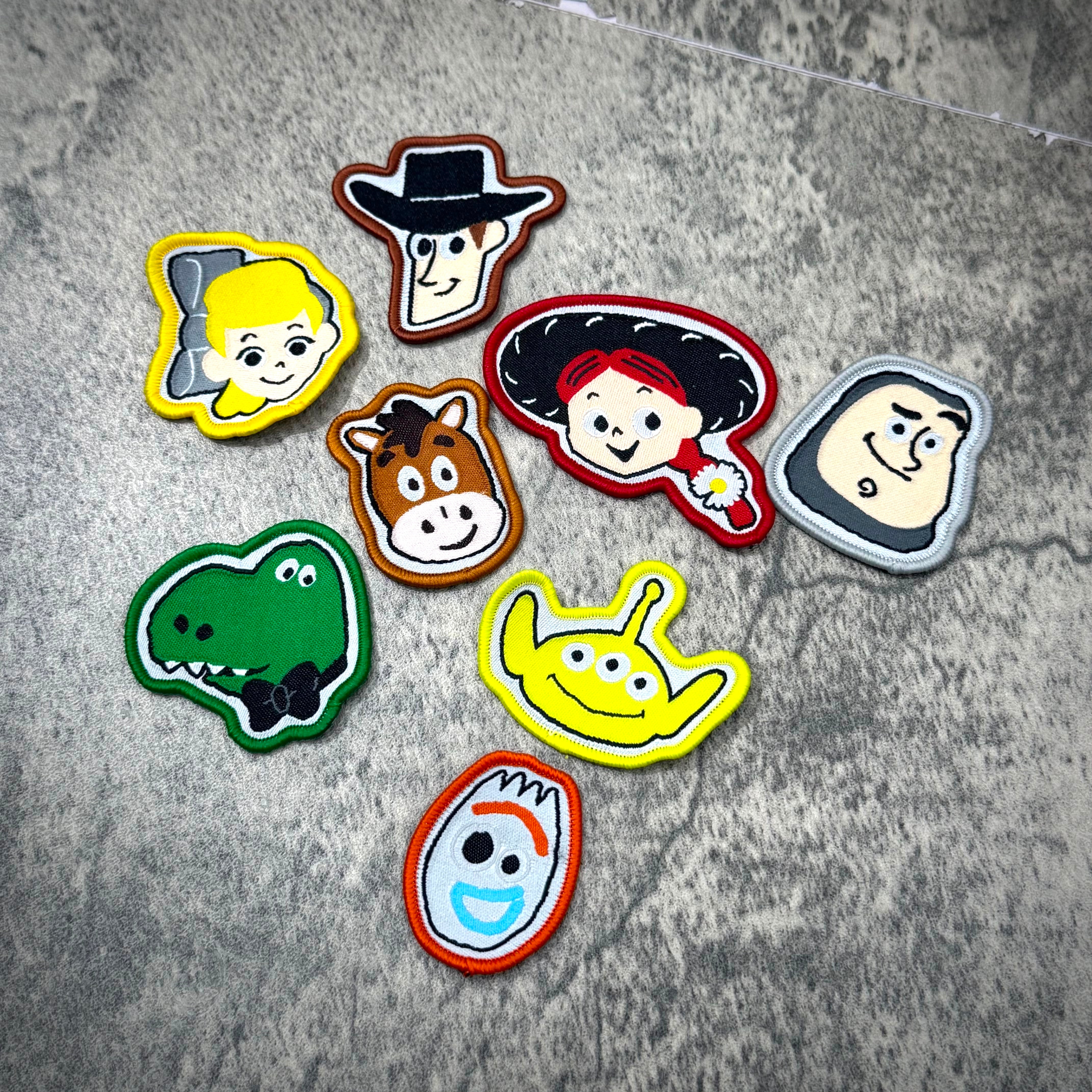 PEACEMINUSONE x Toy Story The First Fan patches featuring characters like Woody, Buzz, and Forky on a textured surface.