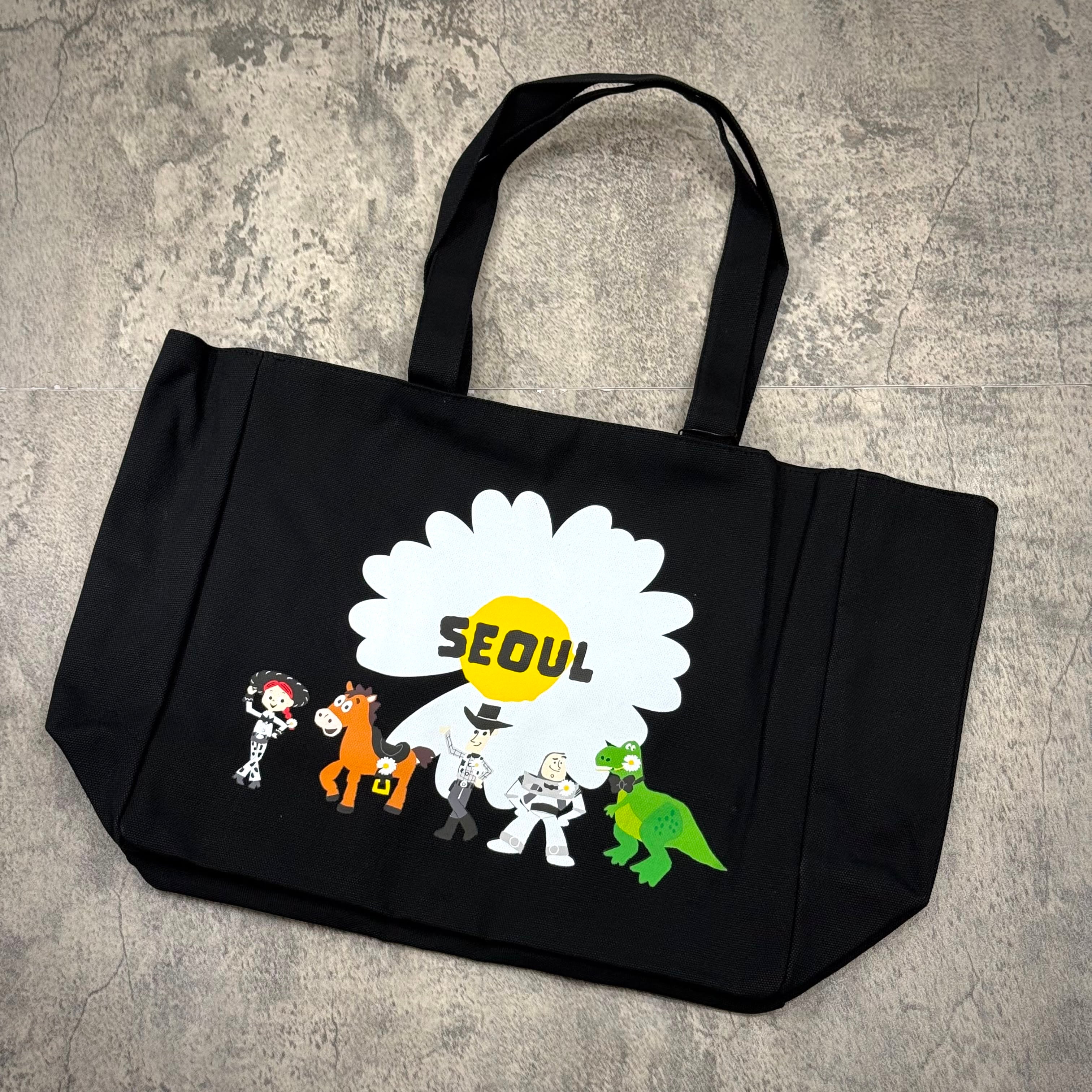 PEACEMINUSONE x Toy Story The First Fan - Tote Bag 02 Seoul featuring colorful characters and the word SEoul on the front.