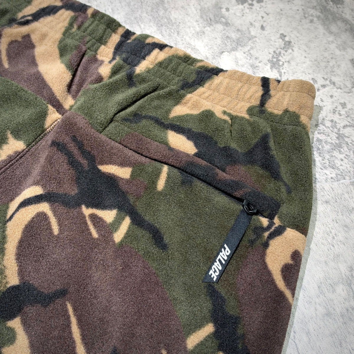 Close-up of Palace P-Surgent Fleece Joggers Black DPM showing camo pattern and emblem on the pocket.
