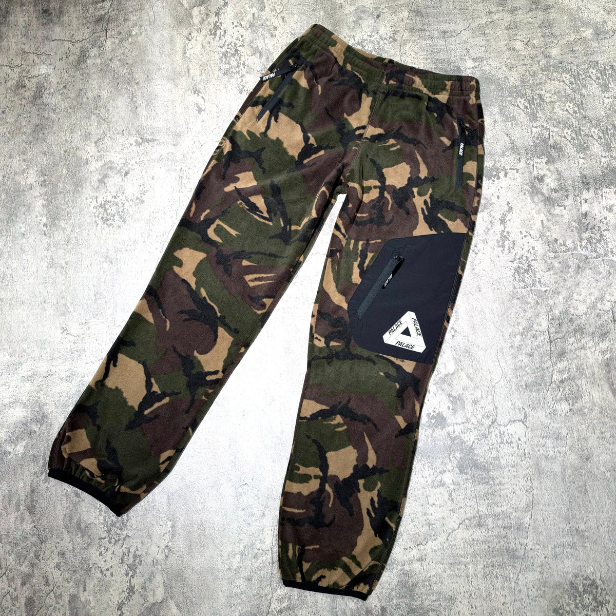 Palace P-Surgent Fleece Joggers Black DPM displayed on a textured surface with a camouflage design.
