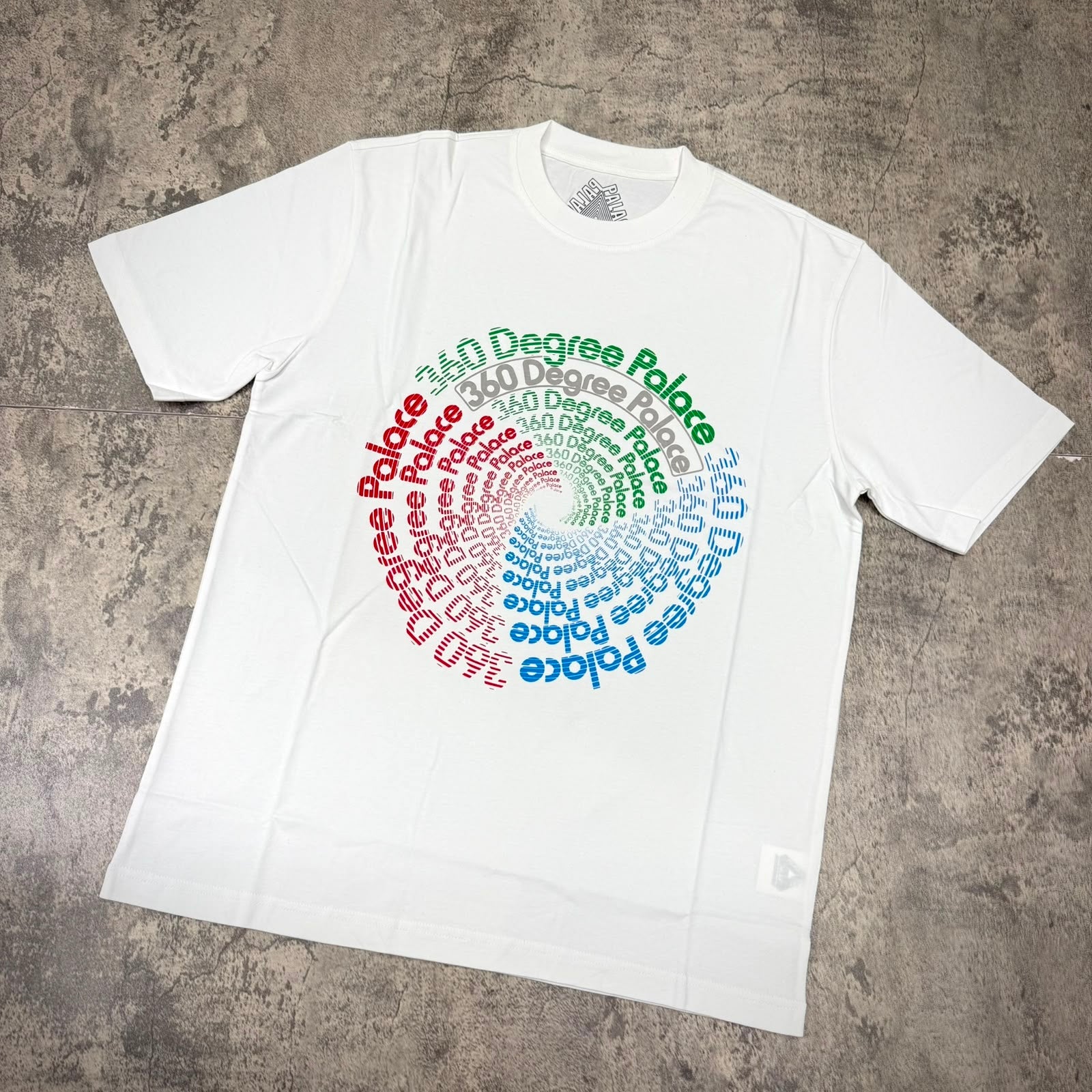 Palace 360 Degree Tee - White featuring a vibrant spiral text design in multiple colors on a plain white shirt.