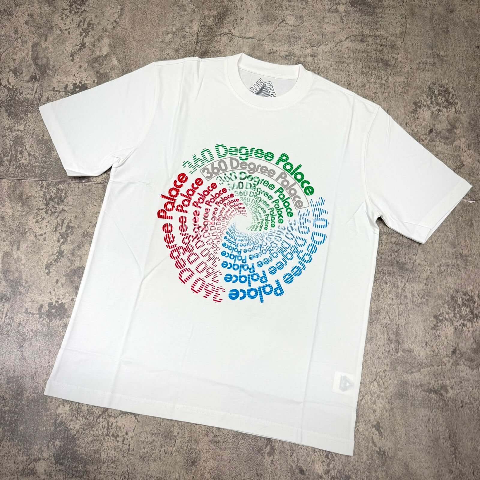 Palace 360 Degree Tee - White featuring a vibrant spiral text design in multiple colors on a plain white shirt.