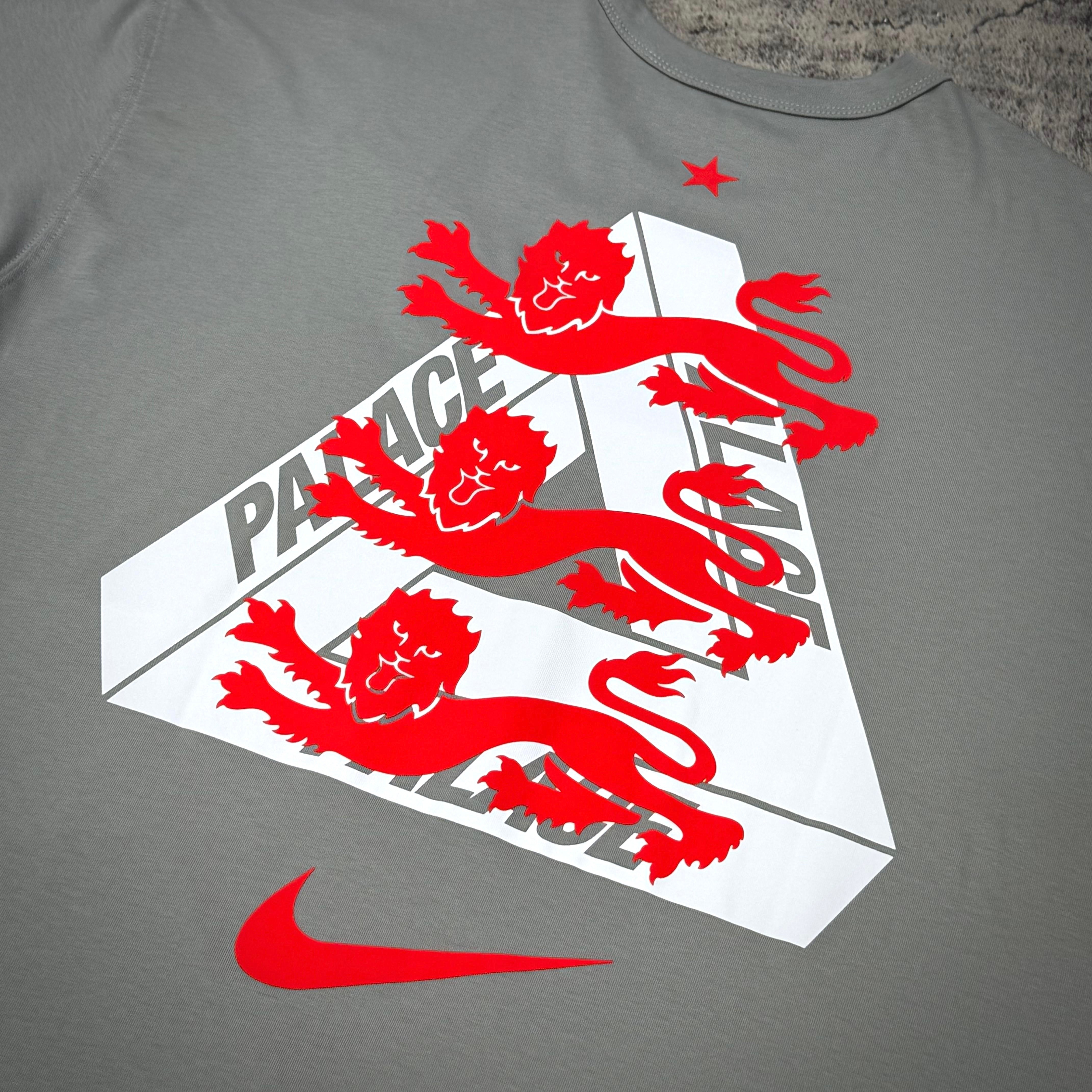 Palace x Nike England Tee featuring bold red lion graphic on a gray background with Nike logo, stylish streetwear design.