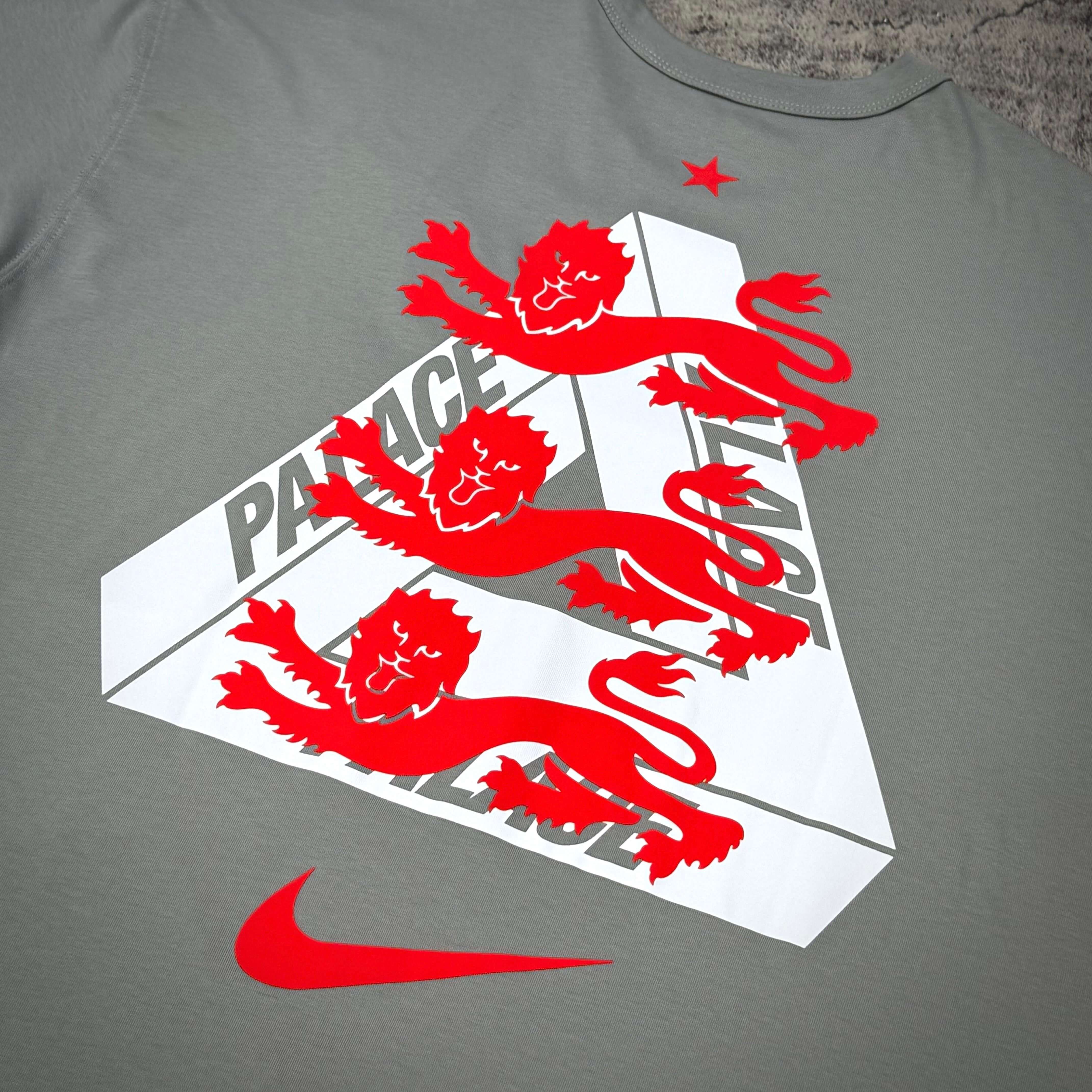 Palace x Nike England Tee featuring bold red lion graphic on a gray background with Nike logo, stylish streetwear design.