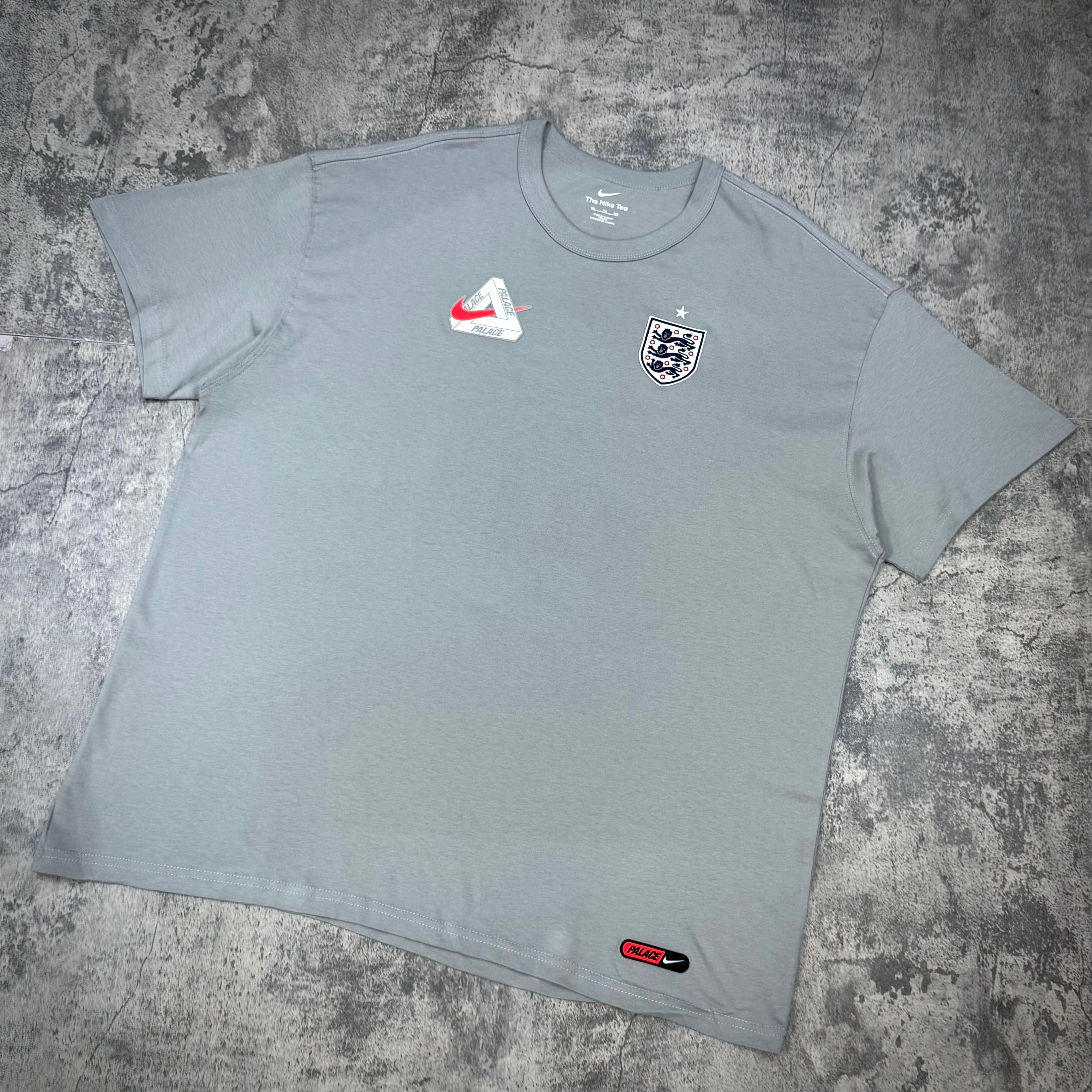 Palace x Nike England Tee in light gray with Nike logo and England crest, featuring relaxed fit and high-quality fabric.