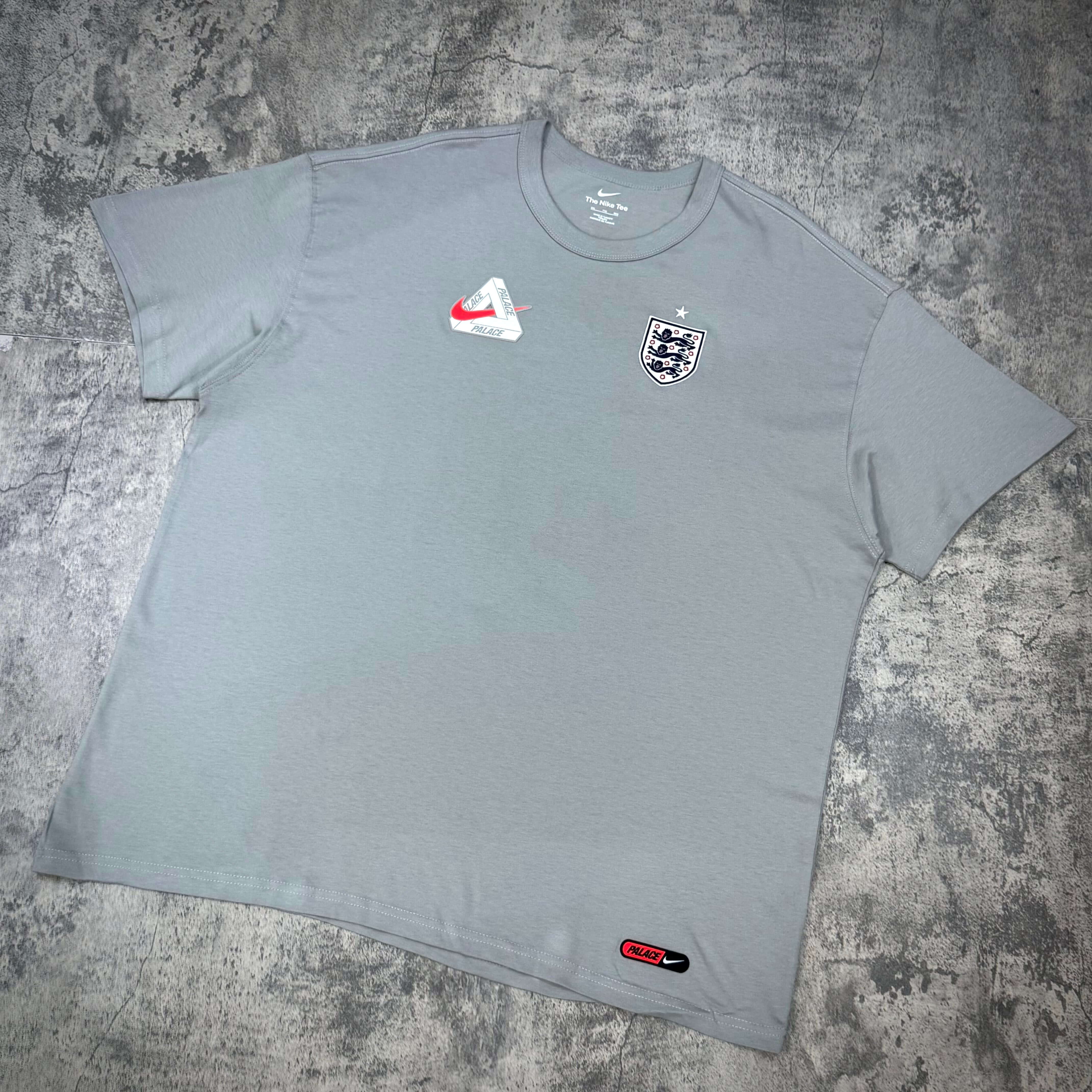 Palace x Nike England Tee in light gray with Nike logo and England crest, featuring relaxed fit and high-quality fabric.