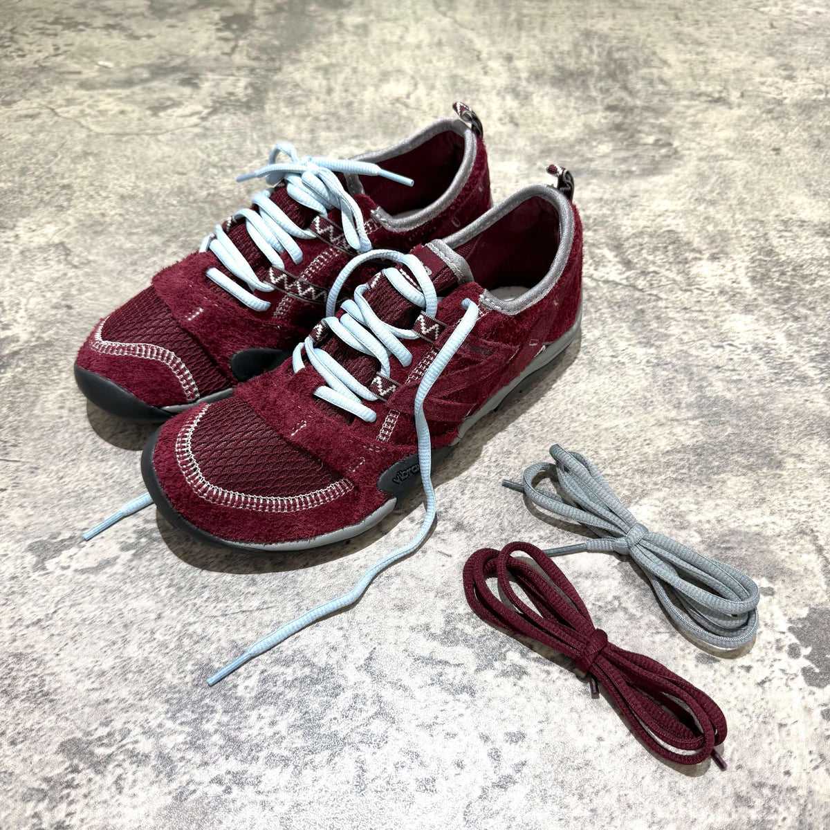 SUNLOVETOUR x New Balance MT1001ND red shoes with multiple lace options laid out.