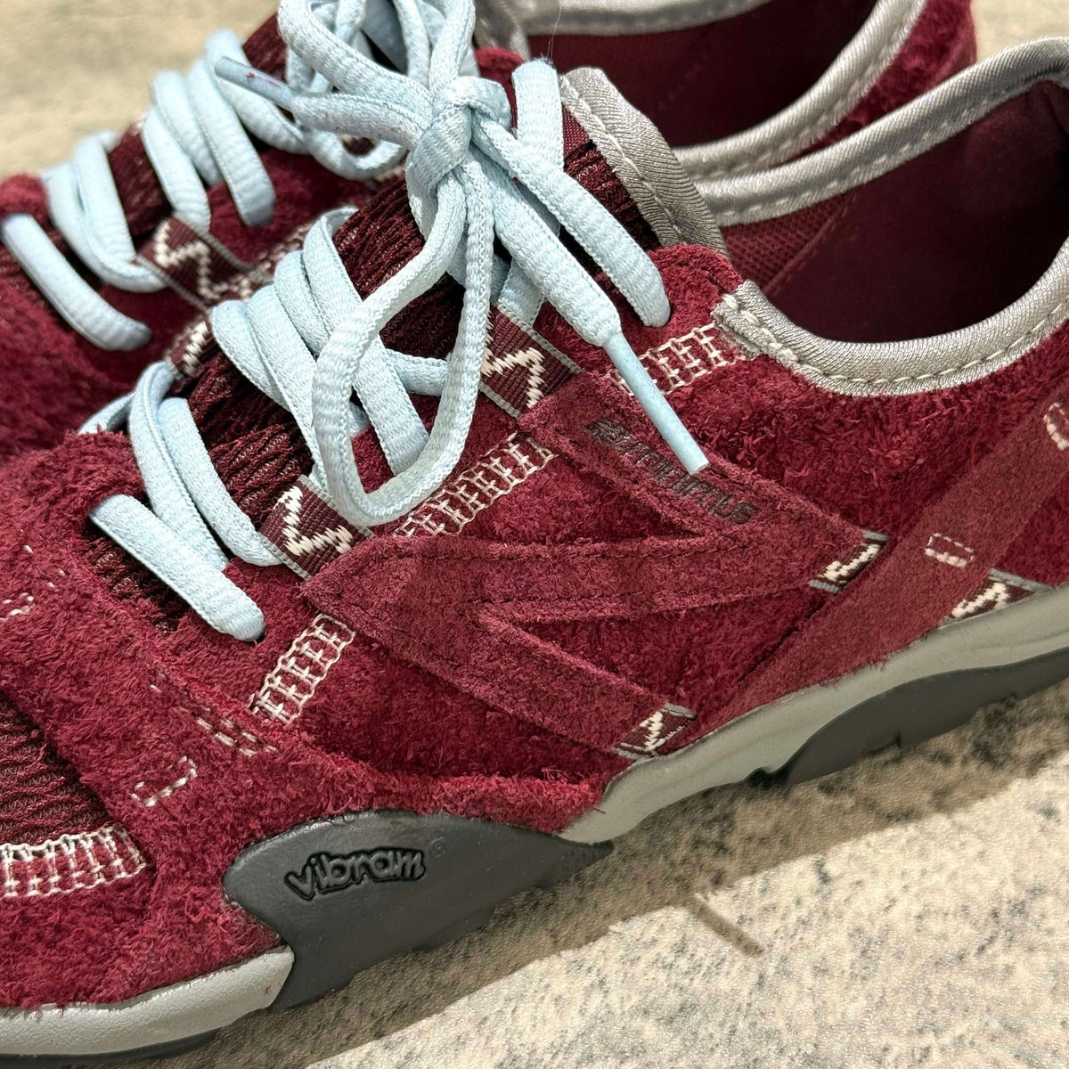 SUNLOVETOUR x New Balance MT1001ND red and grey sneakers with light blue laces and Vibram soles.