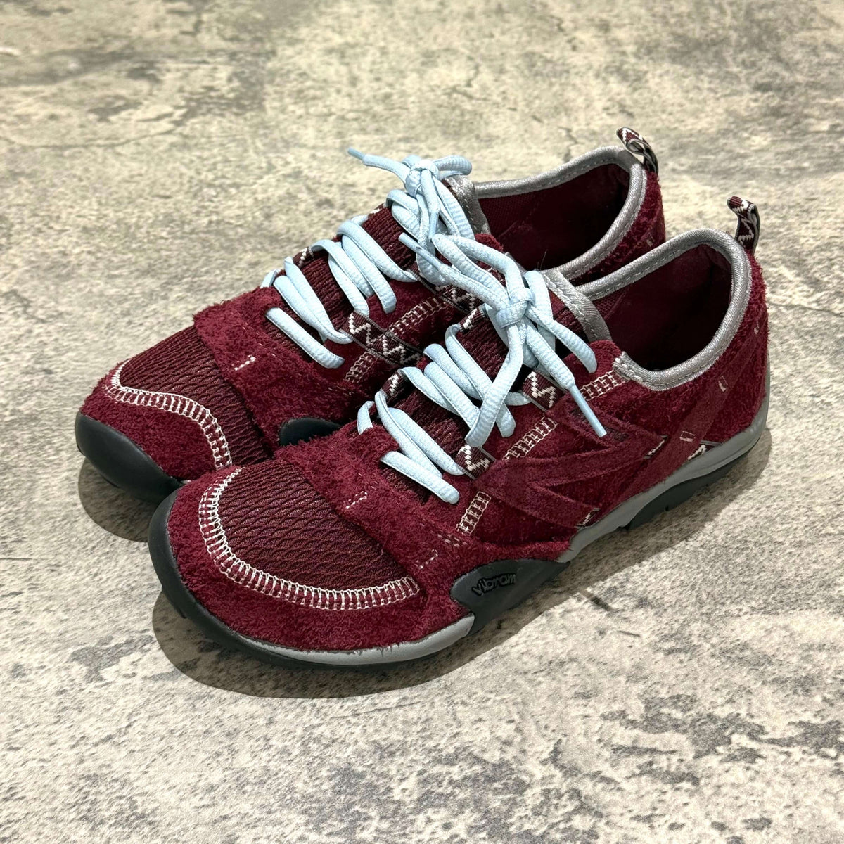 SUNLOVETOUR x New Balance MT1001ND red sneakers with light blue laces on a textured surface.