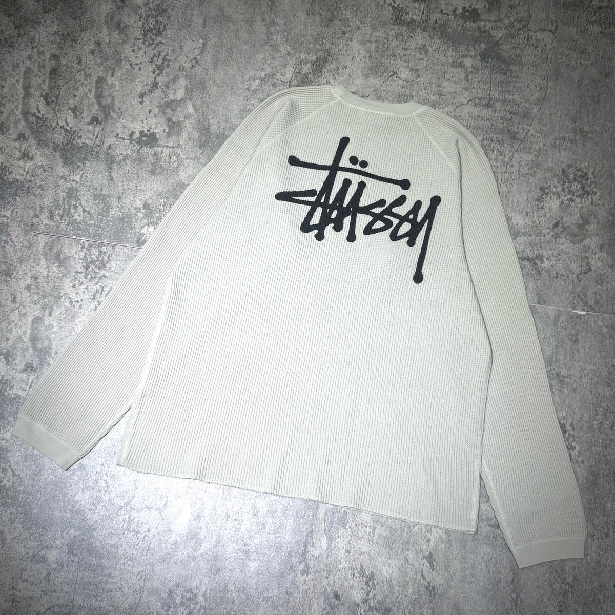Stussy Basic Raglan Thermal LS Crew FW26 in cream color with black logo on the back, casual long sleeve designed for comfort.