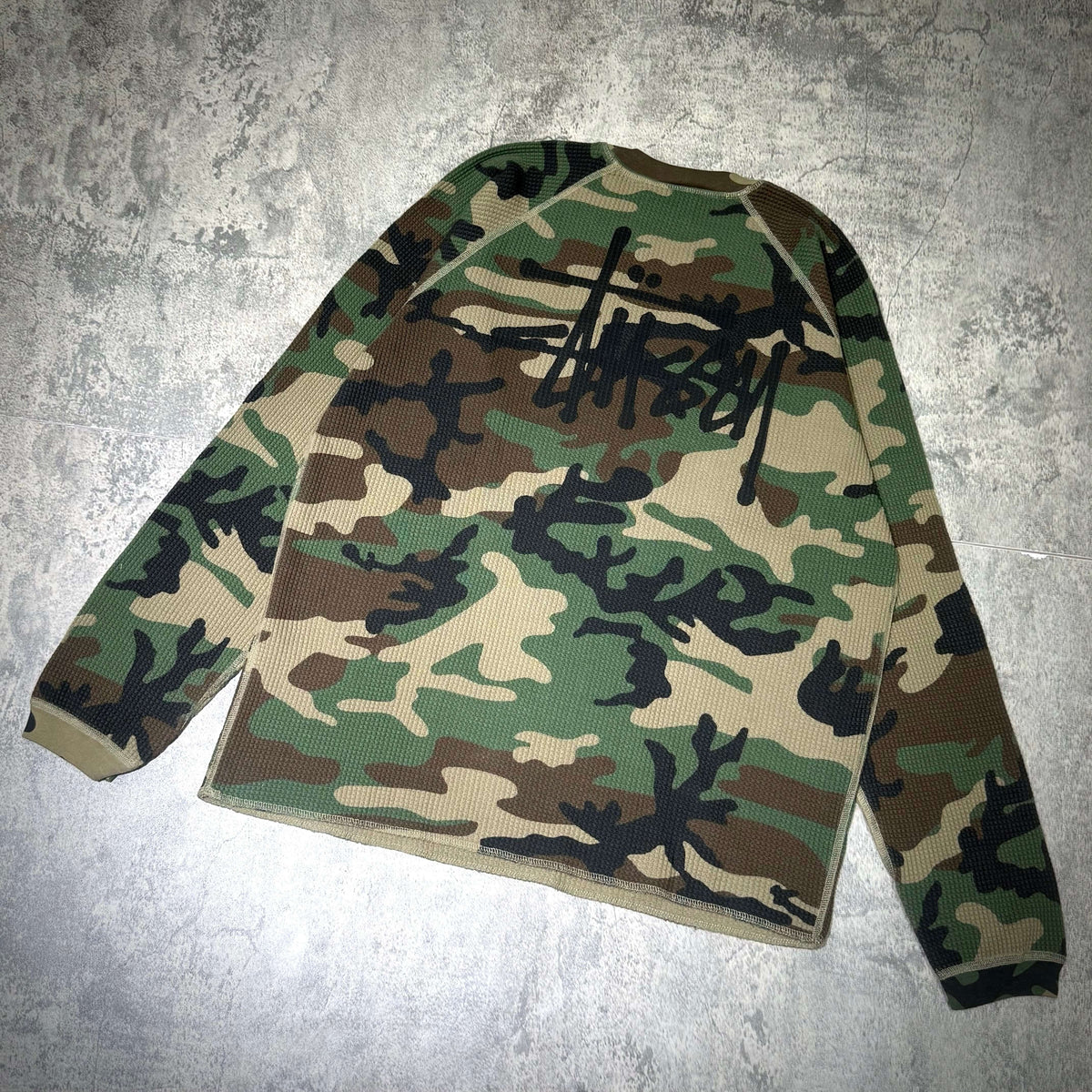 Stussy Basic Raglan Thermal LS Crew FW26 in a camouflage pattern, showcasing a unique design and comfortable fit.