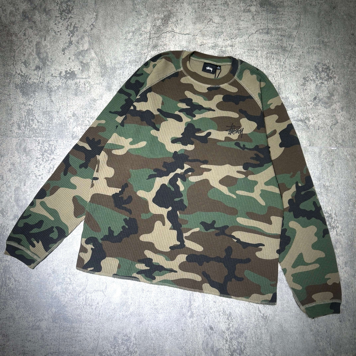 Stussy Basic Raglan Thermal LS Crew FW26 in a camouflage pattern, featuring long sleeves and a comfortable fit.