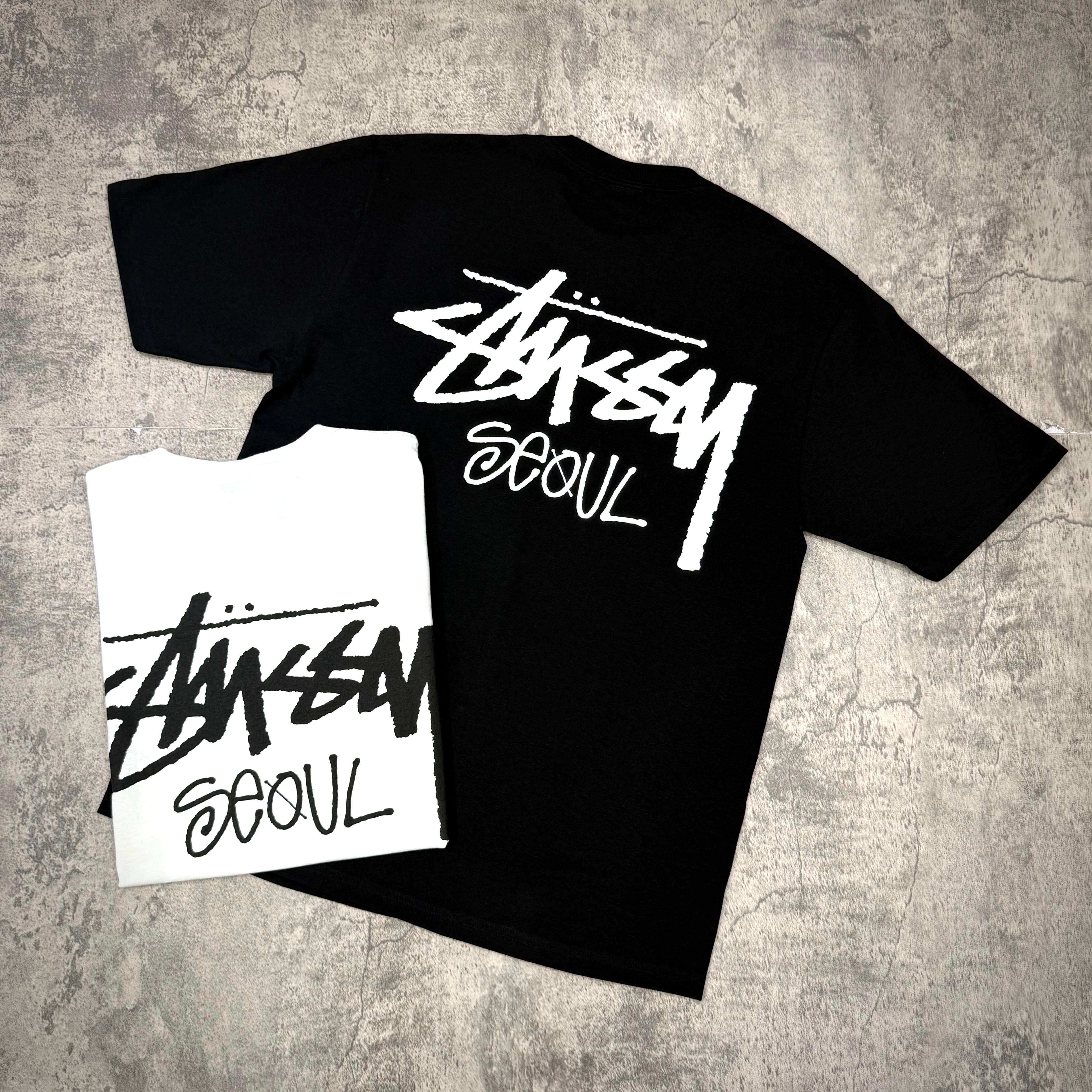 Stussy Seoul Exclusive Logo Tee in black and white, showcasing unique back design and bold branding.