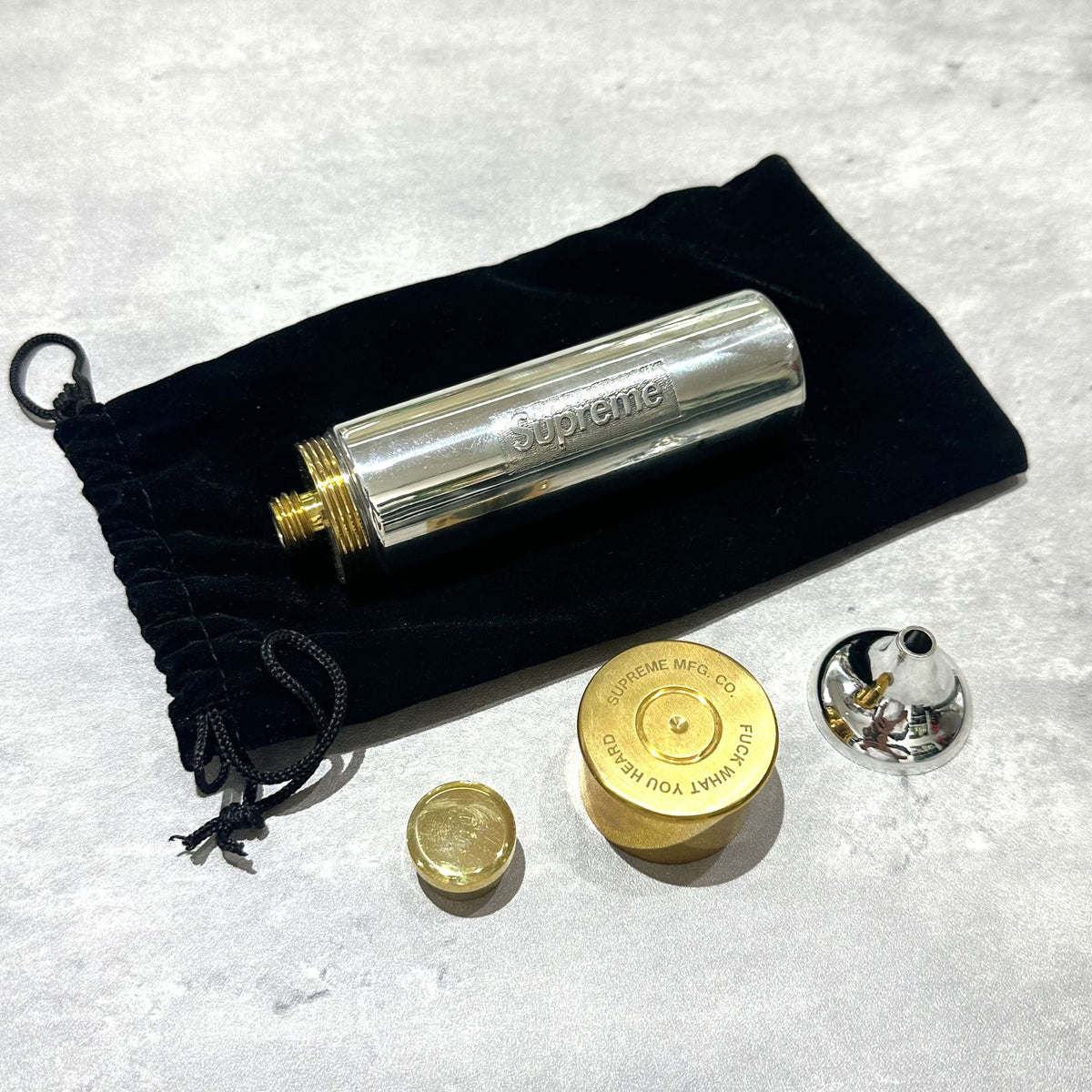 Supreme English Pewter Company Bullet Flask with pouch and accessories on a textured surface.