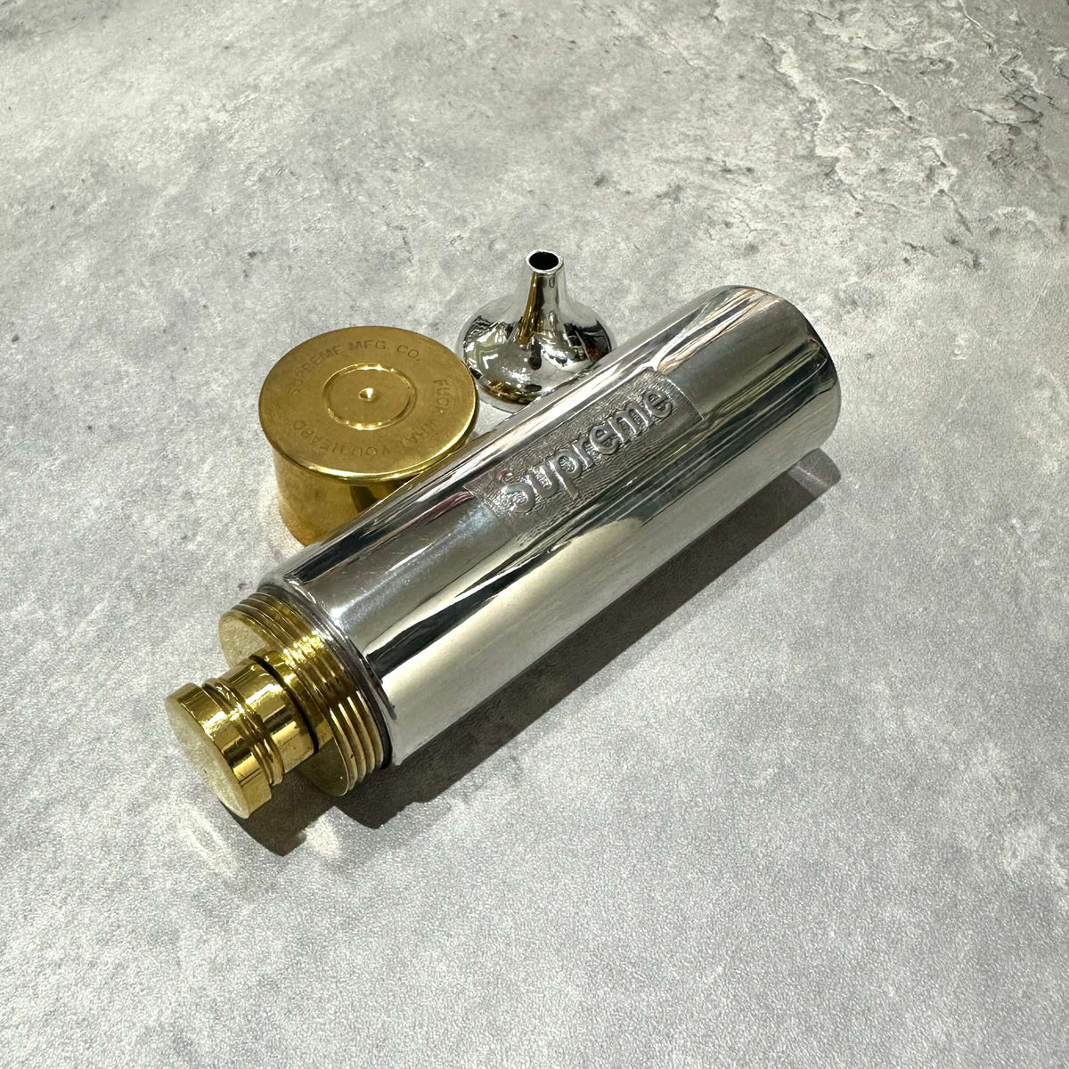 Supreme English Pewter Company Bullet Flask with lid and filler spout on a textured surface.