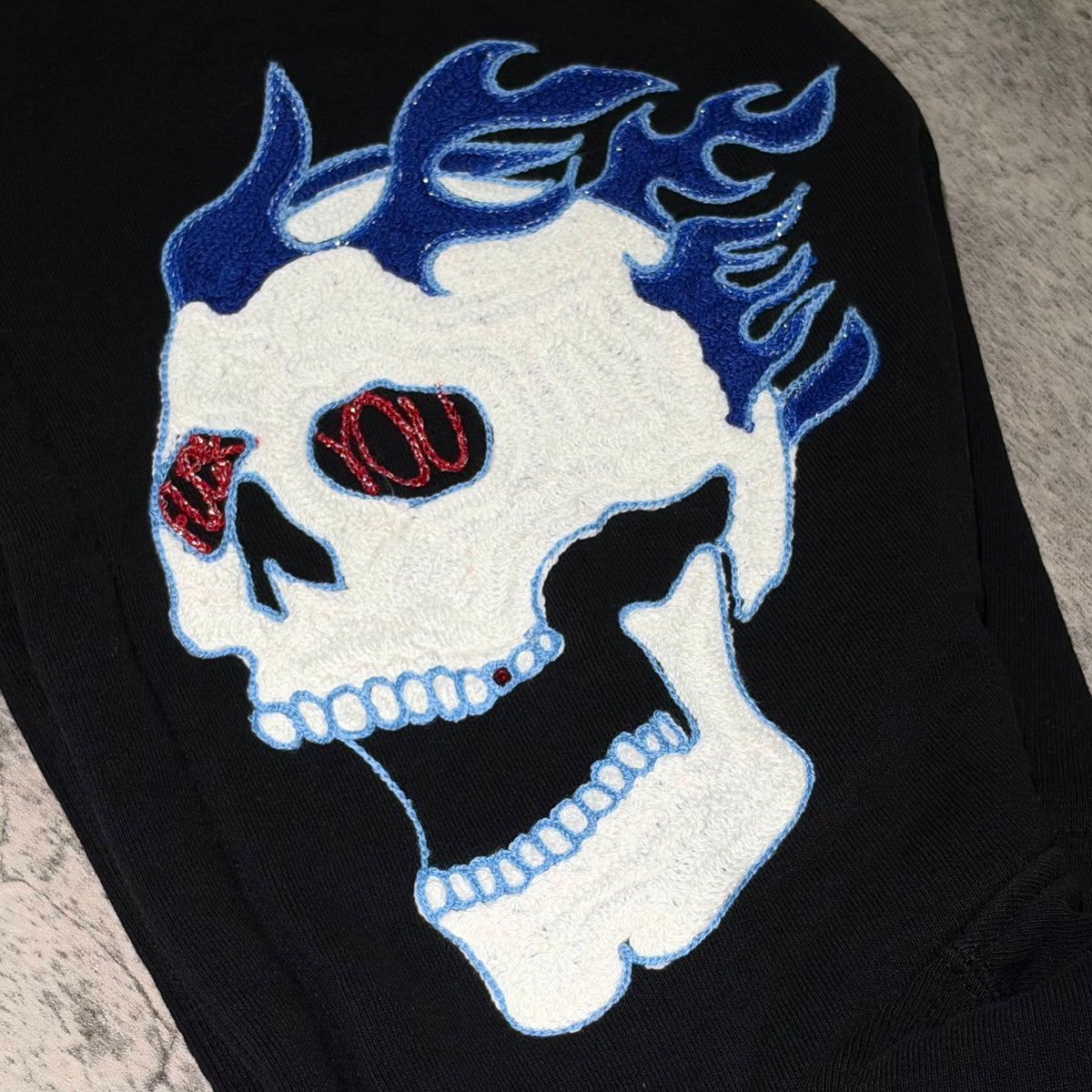 Embroidered skull design with blue flames and red eyes on Supreme Fuck You Zip Up Hooded Sweatshirt.